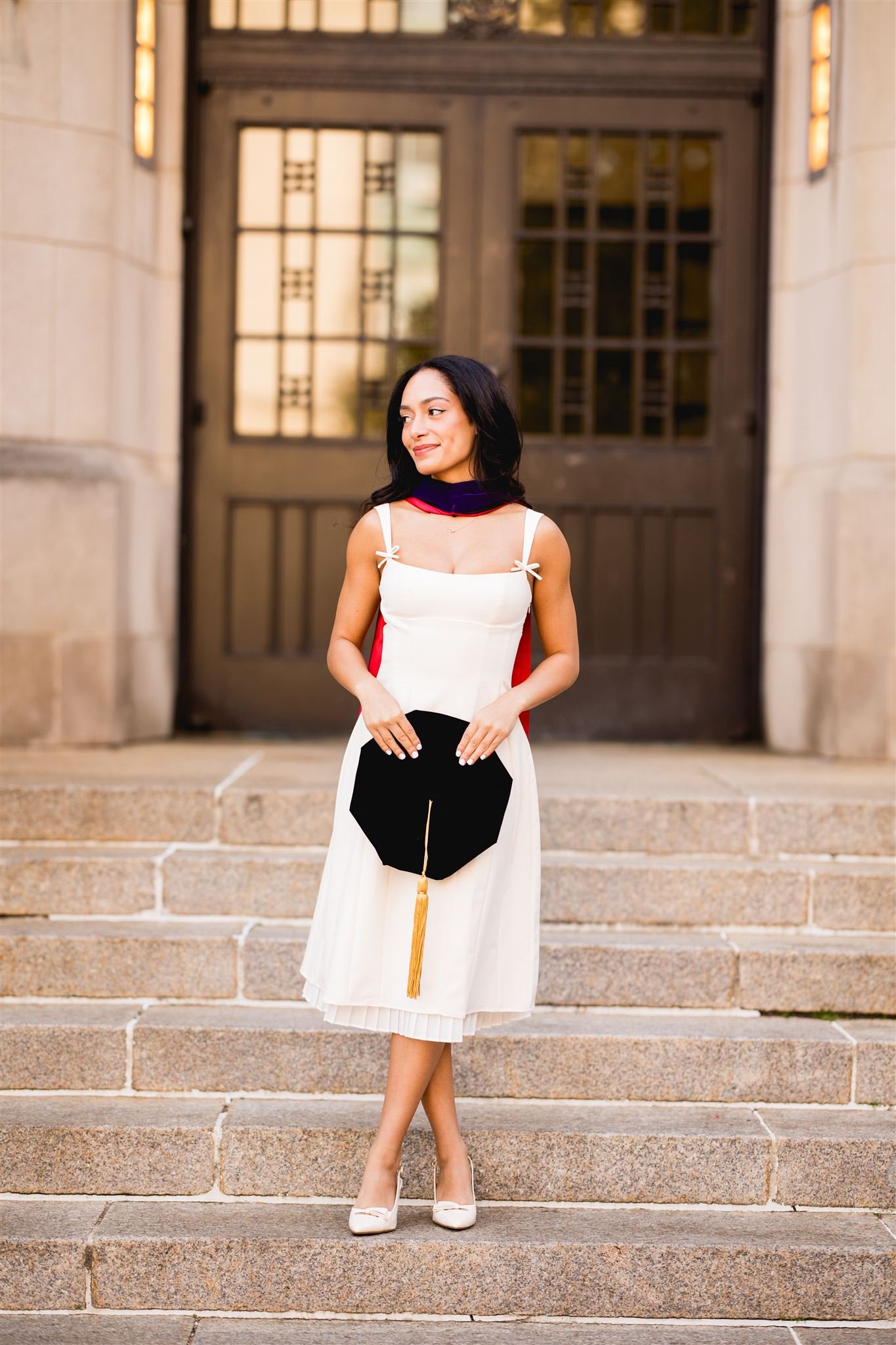 Senior graduate holding a cap while standing on historic stone steps during a graduation photography session in Boston
