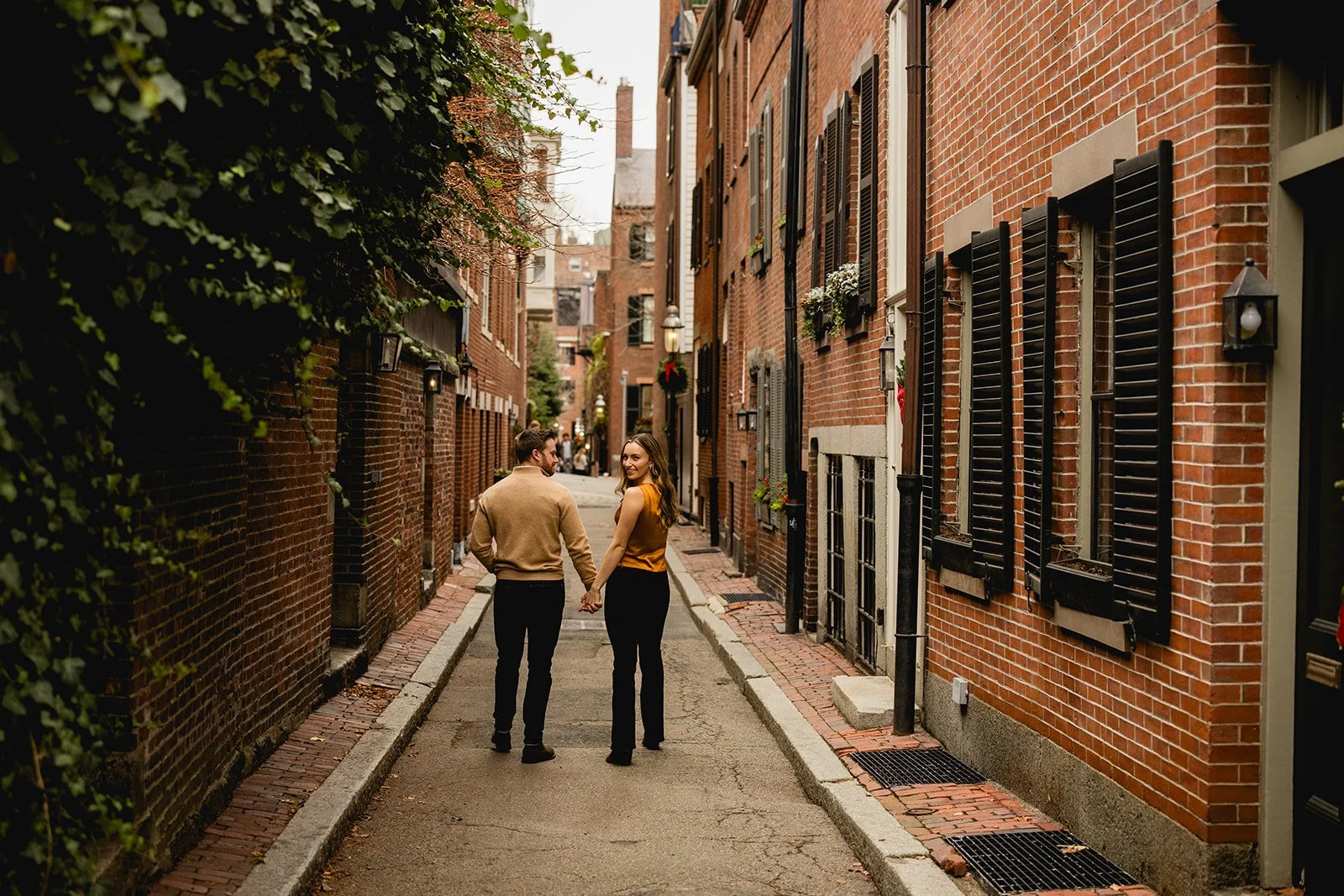 Couple walking down a quiet historic street in Beacon Hill during a Boston engagement photo session.