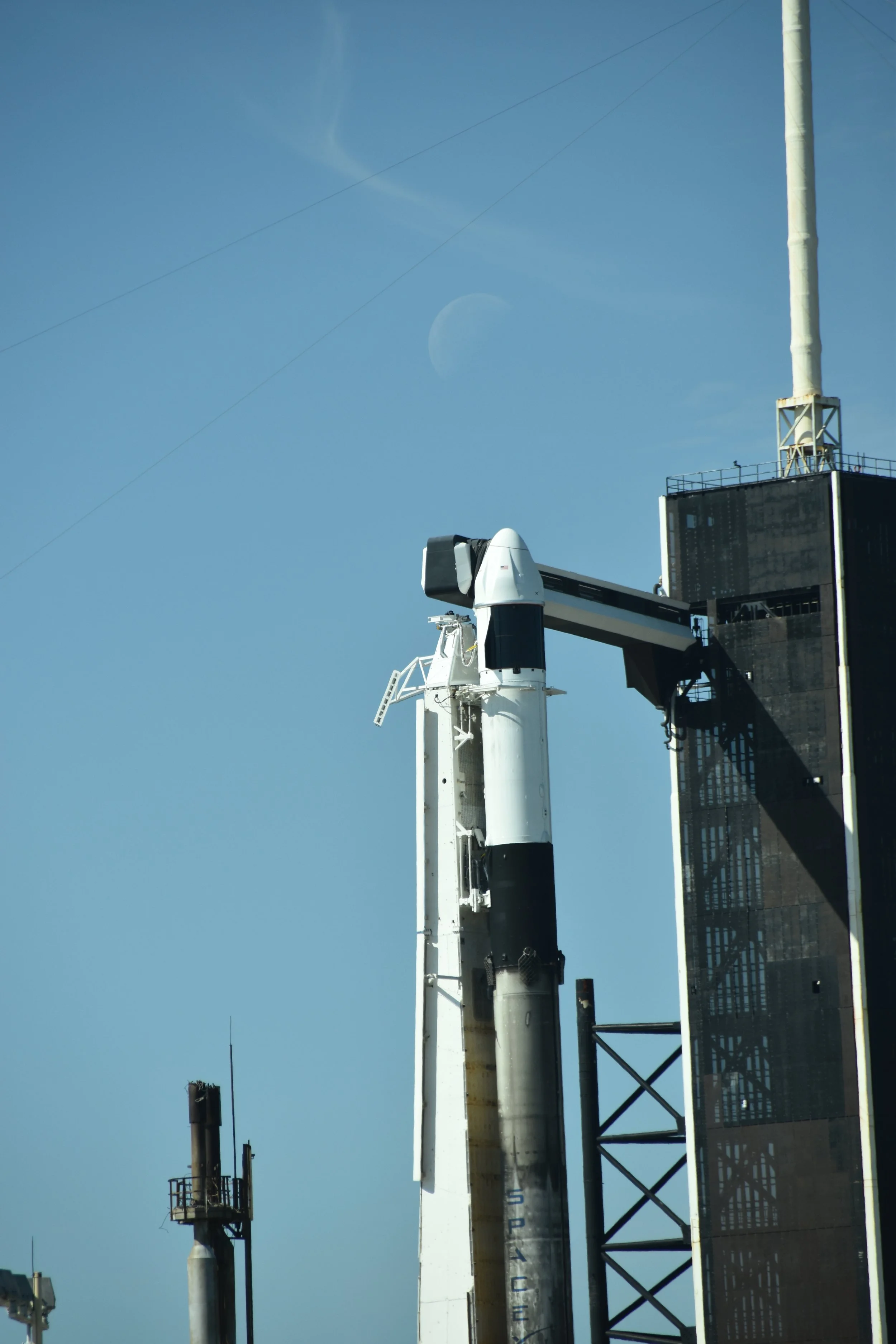 Close-up of a space rocket on a launch pad with a sky and the moon visible in the background.