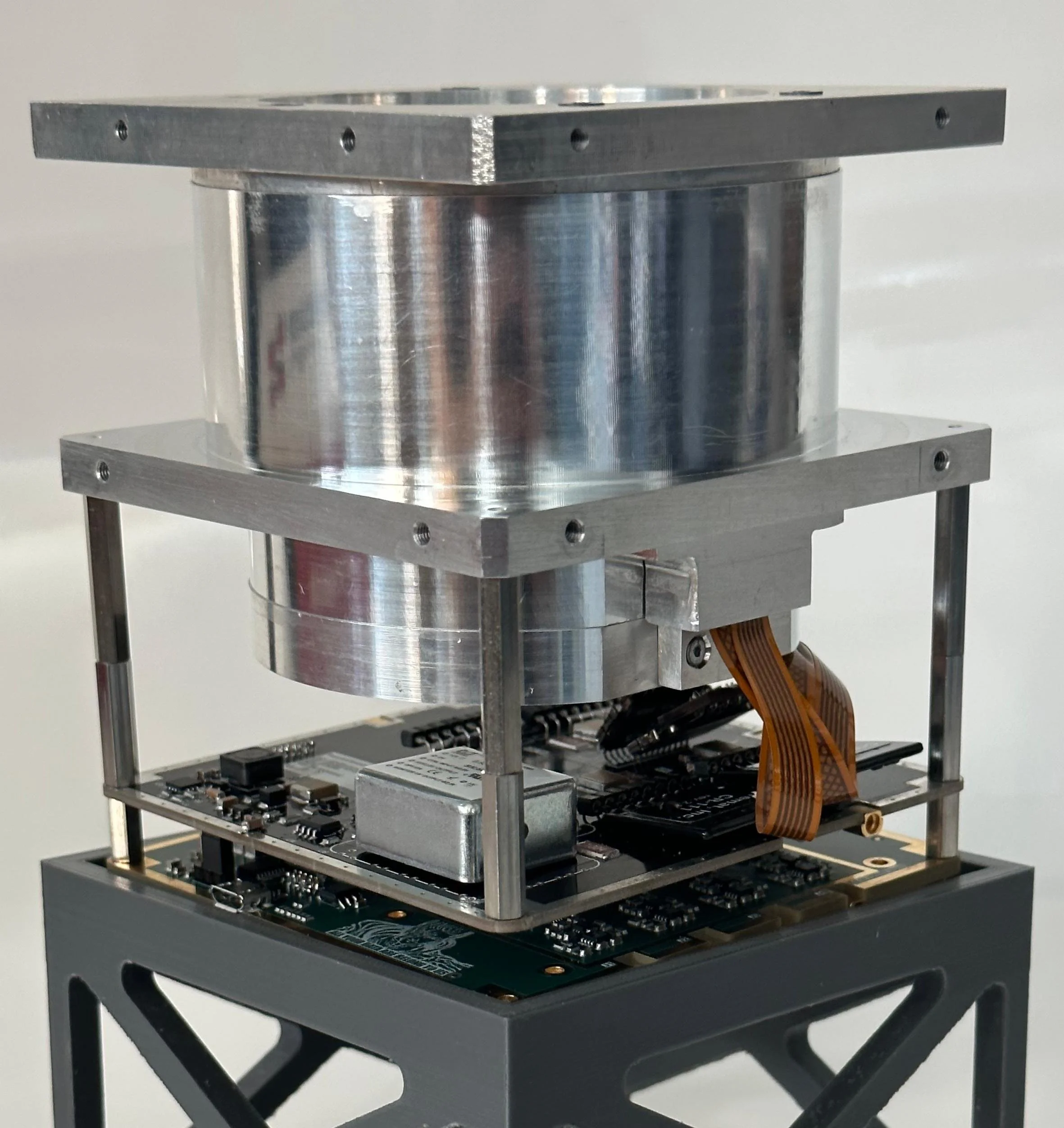 A close-up of a mechanical device with metal components and a circuit board, likely a scientific instrument or robotic component.