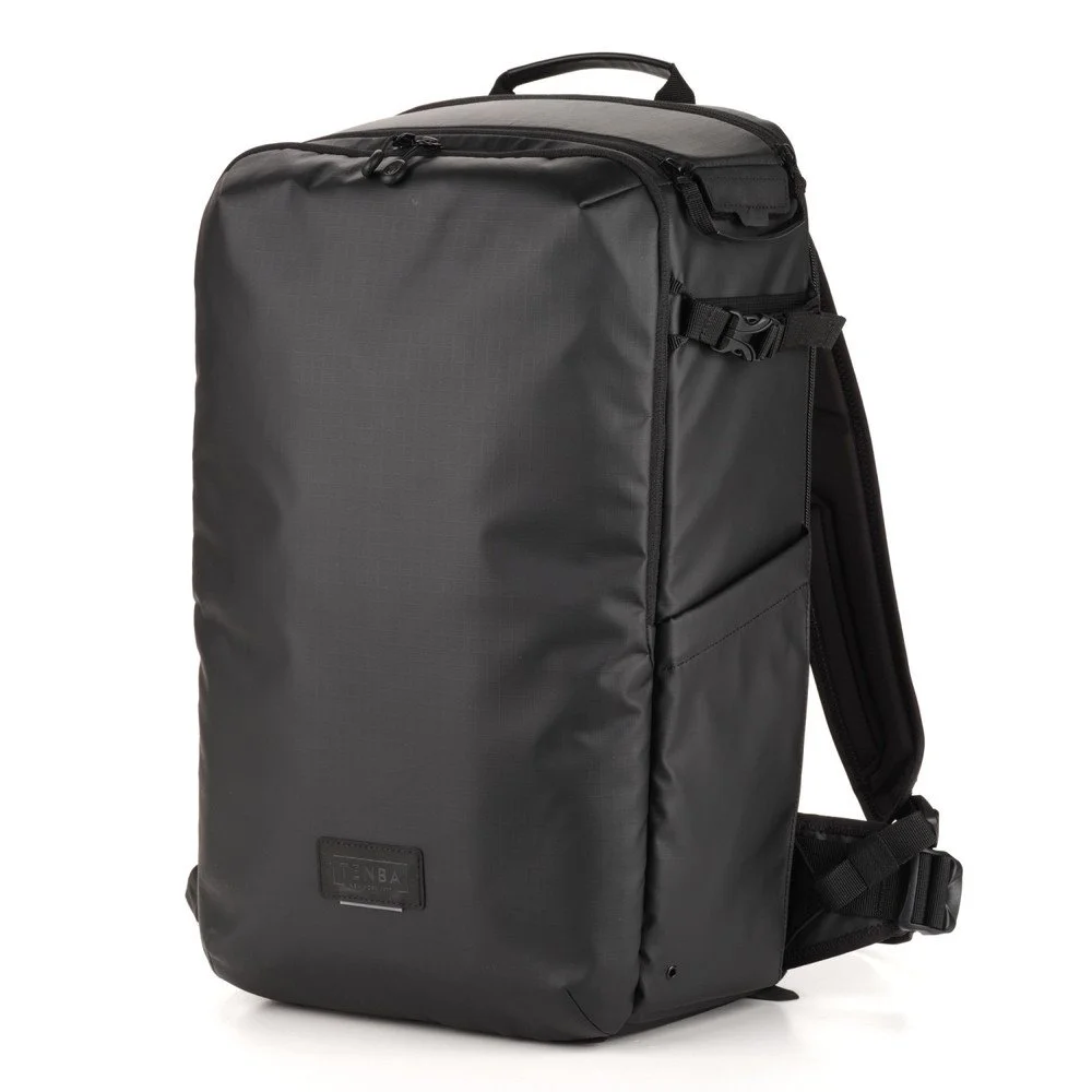 A black, rectangular backpack with multiple zipper compartments and adjustable shoulder straps.