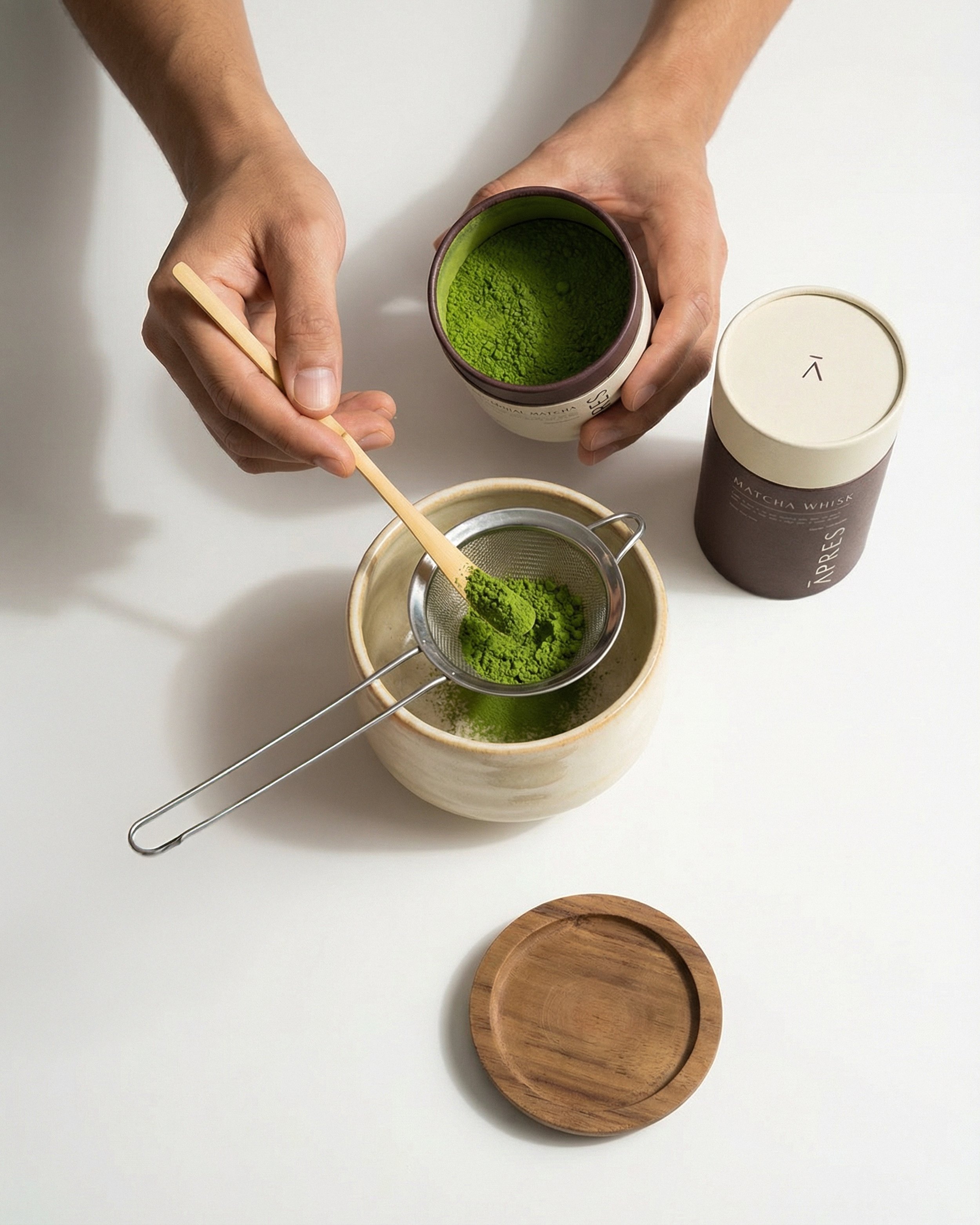 Premium-minimalist-matcha-ritual-scene.-Top-down-flat-lay-on-a-clean-white-surface.-Soft-natural-daylight-with-gentle-shadows.-Hands-preparing-matcha-–-one-hand-holding-a-small-jar-o-(1)web.jpg