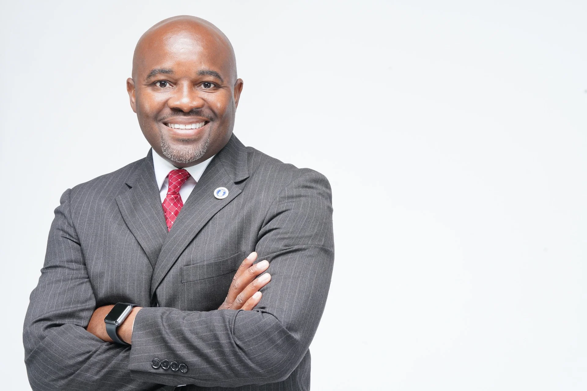 Moses Delaney standing while dressed in a suit and smiling.  This photo is used as the main image for the Campus President training program offered by the National Institute for Higher Education Training.