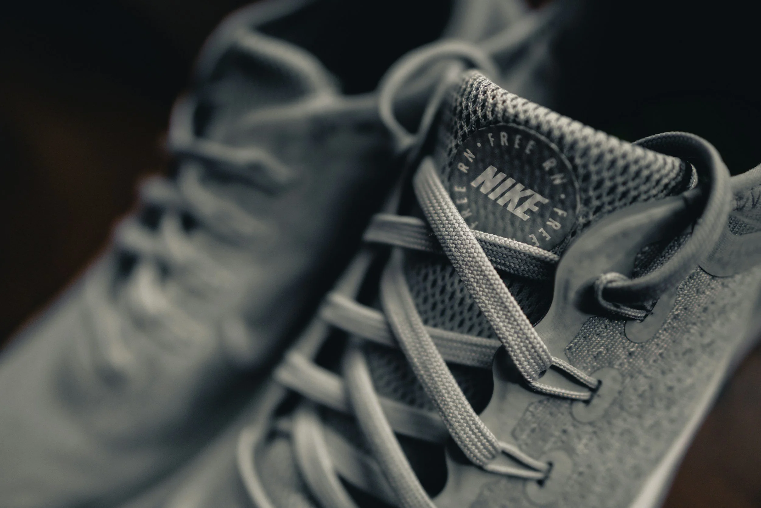 Close-up of a pair of gray Nike athletic shoes with laces, focusing on the tongue with the Nike logo and text.