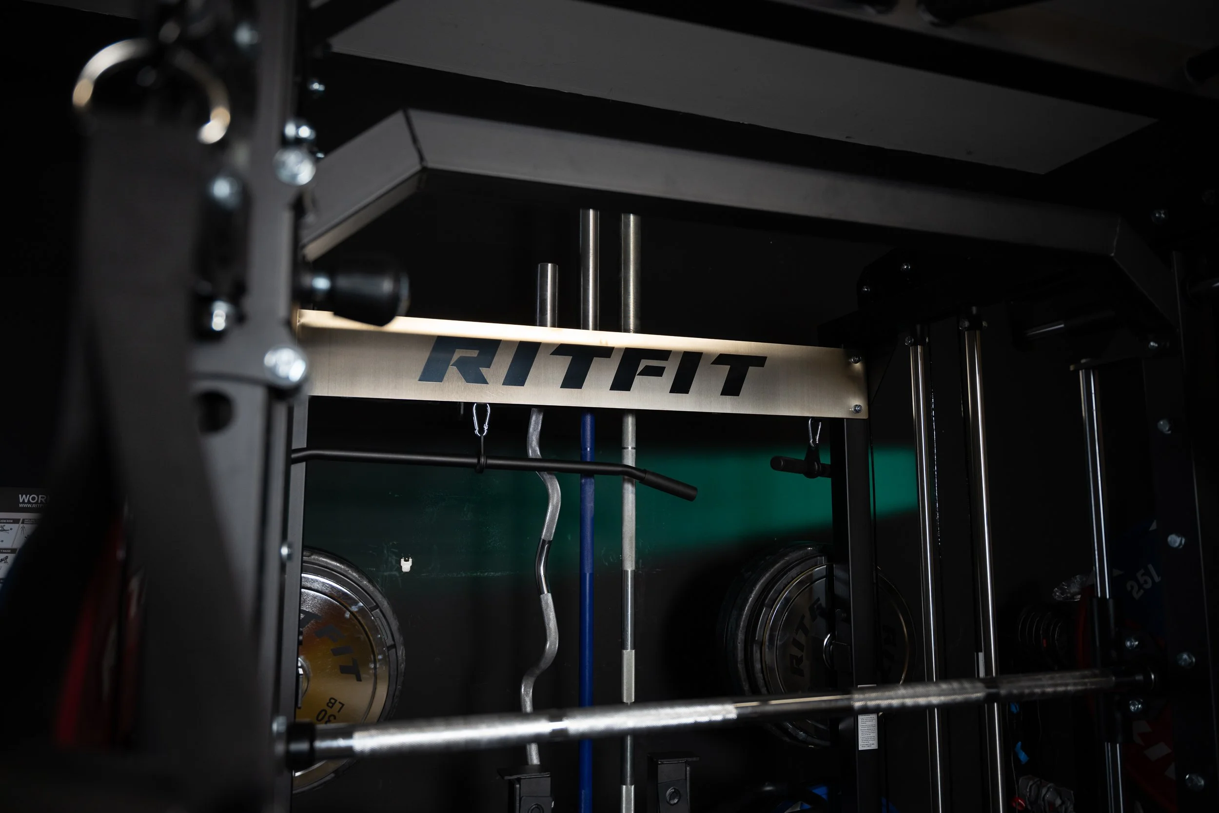 Close-up of a piece of gym equipment with weights and the word 'RITFIT' on a metal bar.