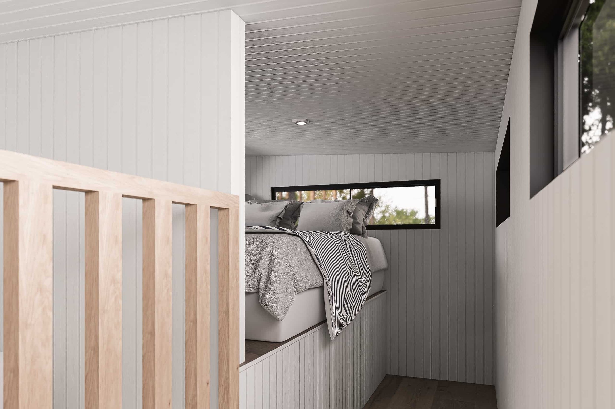 A modern bedroom with white paneled walls and ceiling, a window with a view of trees, a bed with gray blankets and striped pillowcases, and a wooden railing at the foot of the bed.