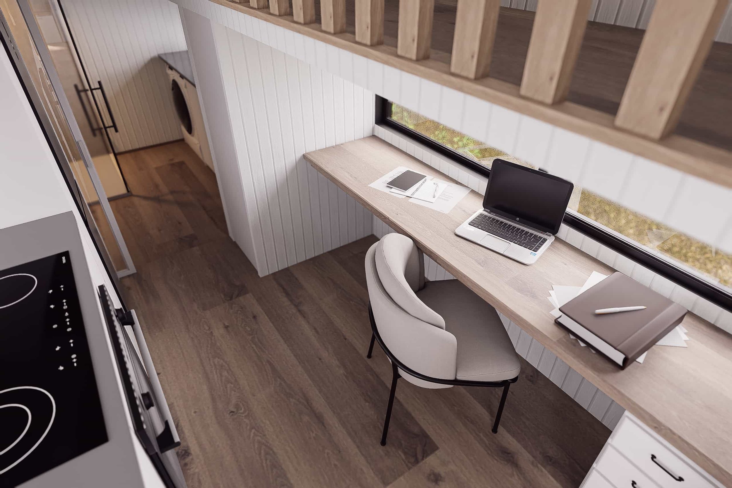 Home office workspace with a laptop, notebooks, and a chair beneath a large window, next to a kitchen with an electric stove.