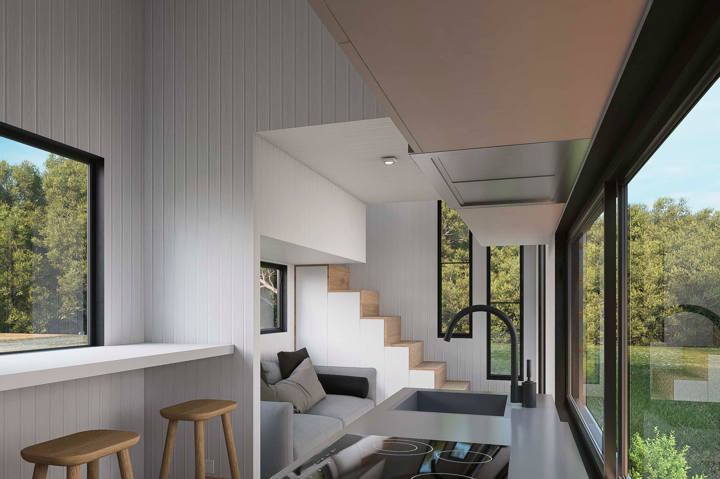 Modern kitchen and living space with large windows, white walls, light wood accents, a gray sofa, and a staircase leading upstairs.