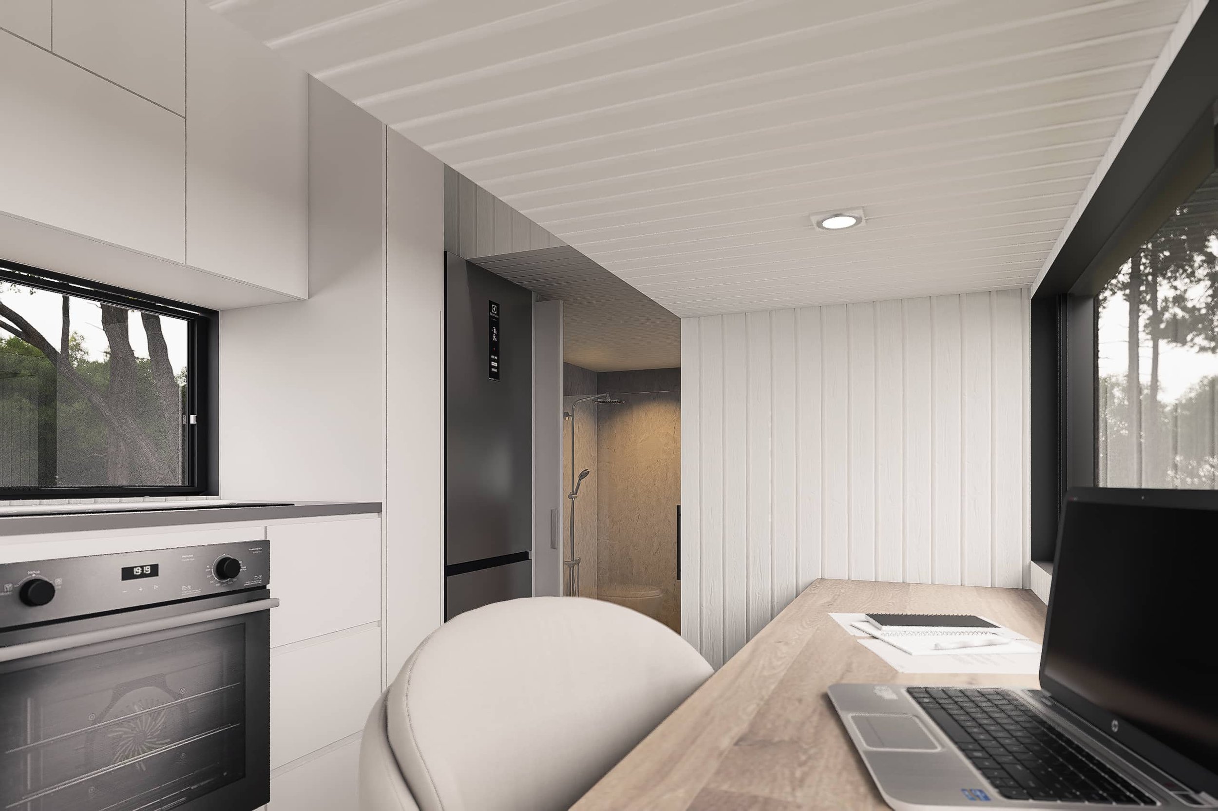 Modern kitchen with white cabinets, a window with a view of trees, a black oven, a refrigerator, and a workspace with a laptop, notebooks, and a pen.