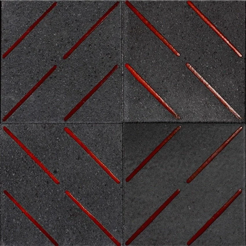 Four dark gray square tiles arranged in a larger square, with red sticks arranged in geometric patterns on top.