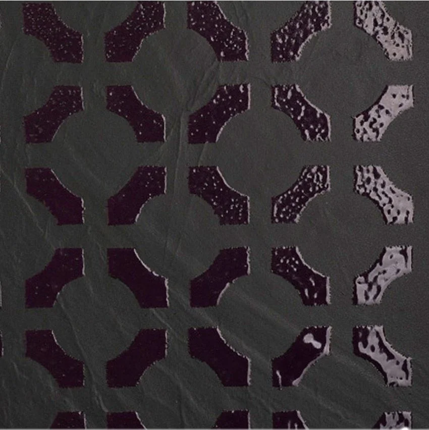 Close-up of a dark, textured surface with a pattern of cut-out circles and irregular shapes.