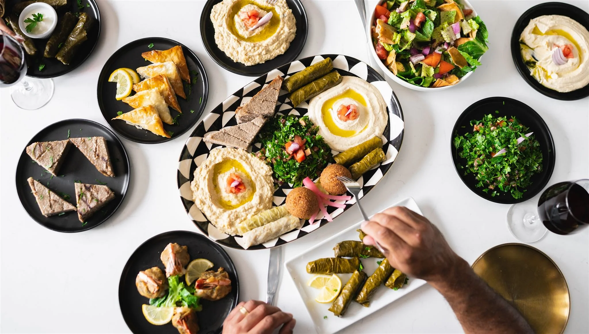 A table spread with hommus, grape leaves, salads and kabobs