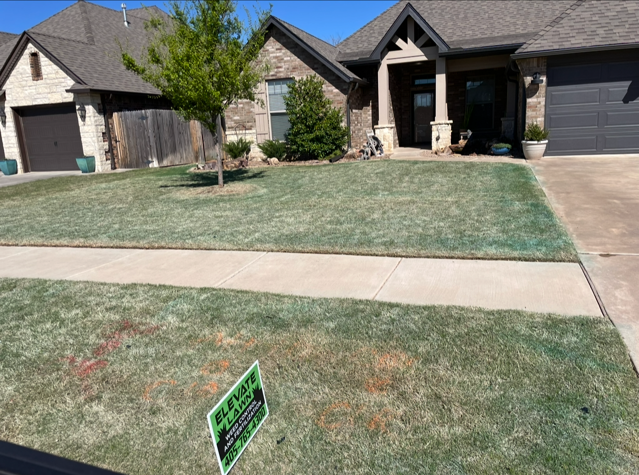 Suburban brick house with a treated lawn and Elevate weed and fertilization control yard sign.