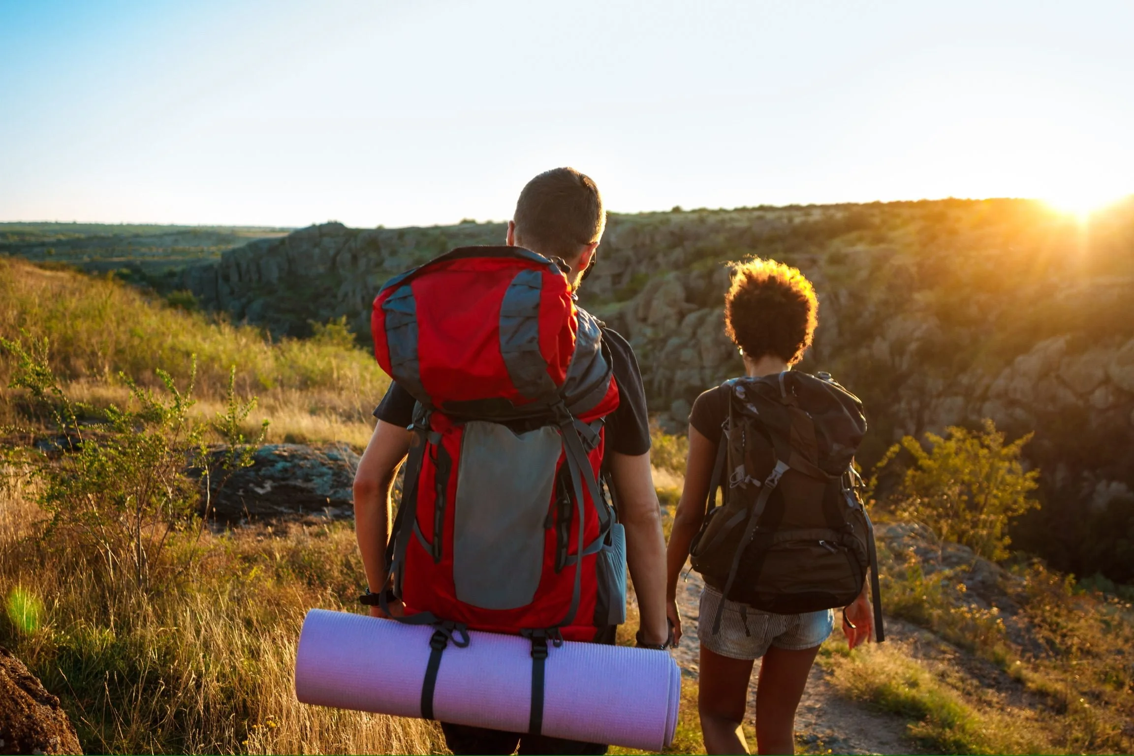 Two hikers with backpacks standing on a scenic overlook at sunset, representing Sierra Summit Foundation’s mission to expand outdoor access, confidence, and life-changing trail experiences.