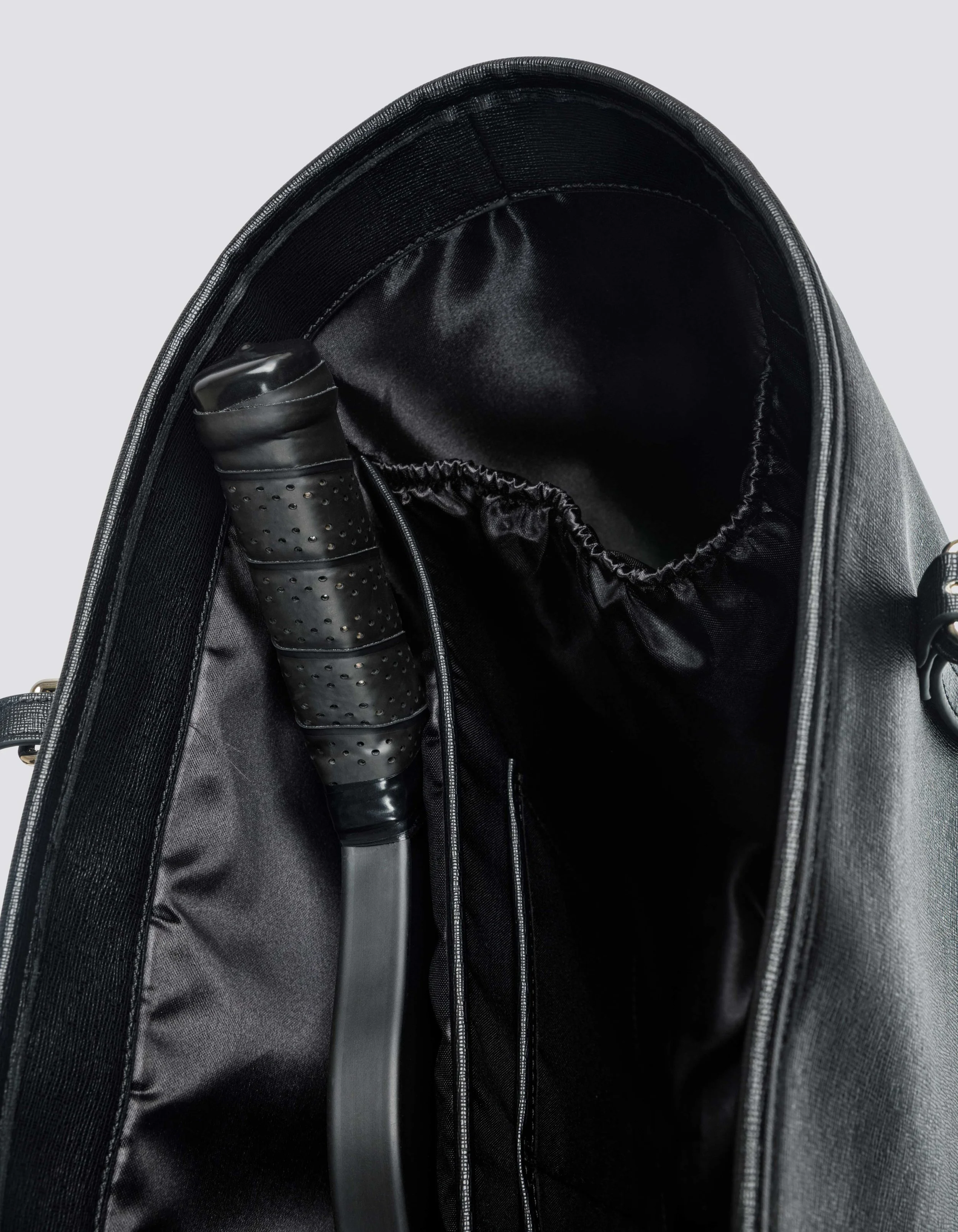 The image shows the interior of a black backpack with a padded strap, a zippered pocket, and a drawstring compartment.