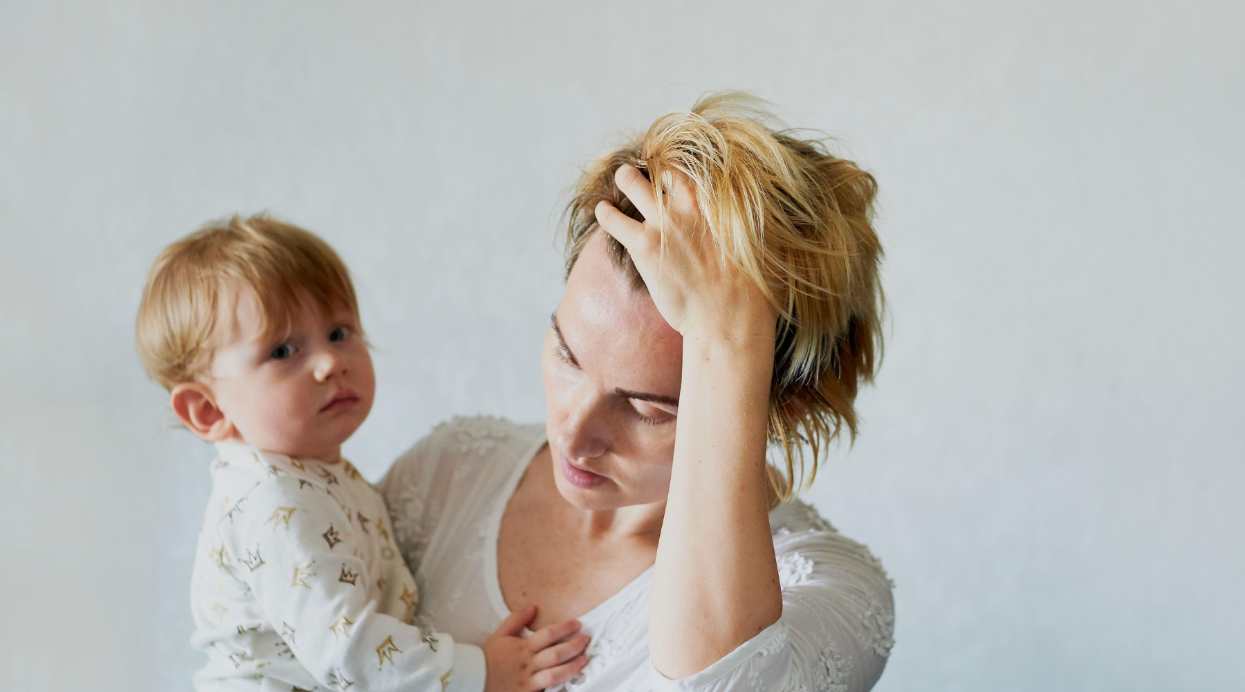 Exhausted mother experiencing mom burnout symptoms including emotional numbness and physical exhaustion beyond normal overwhelm