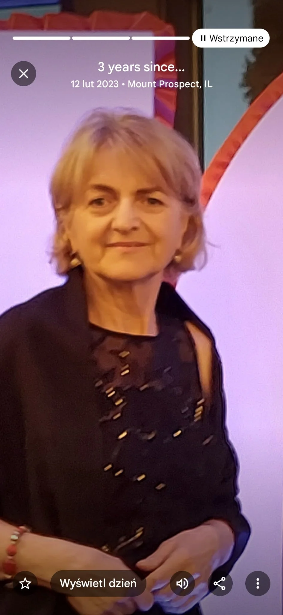 A woman in a black blazer holding a microphone and a colorful booklet about the Disney Junior Minnie Mouse show, standing near an exit sign in an indoor setting.
