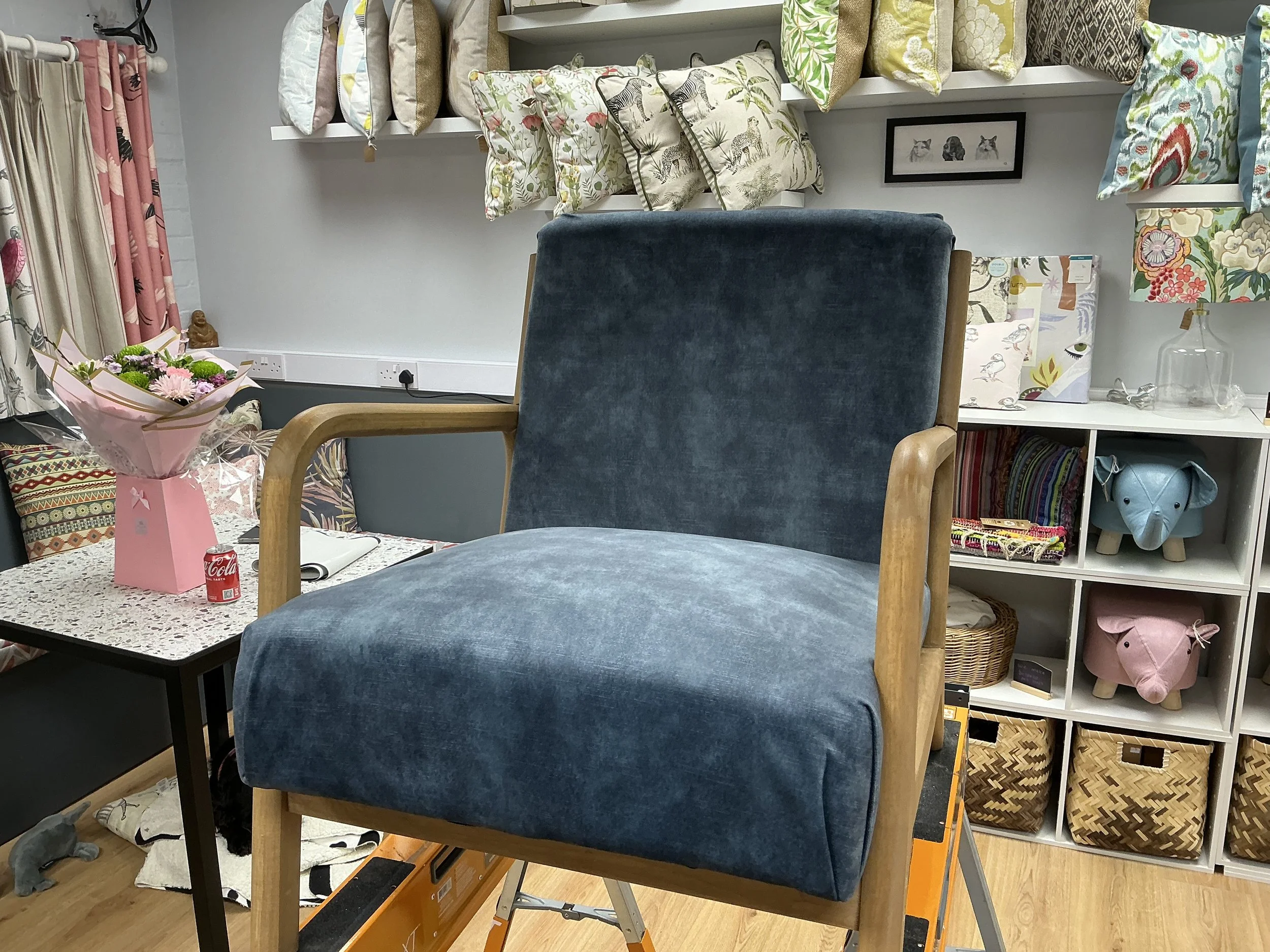 Furniture store with blue armchair and decorative pillows on shelves.
