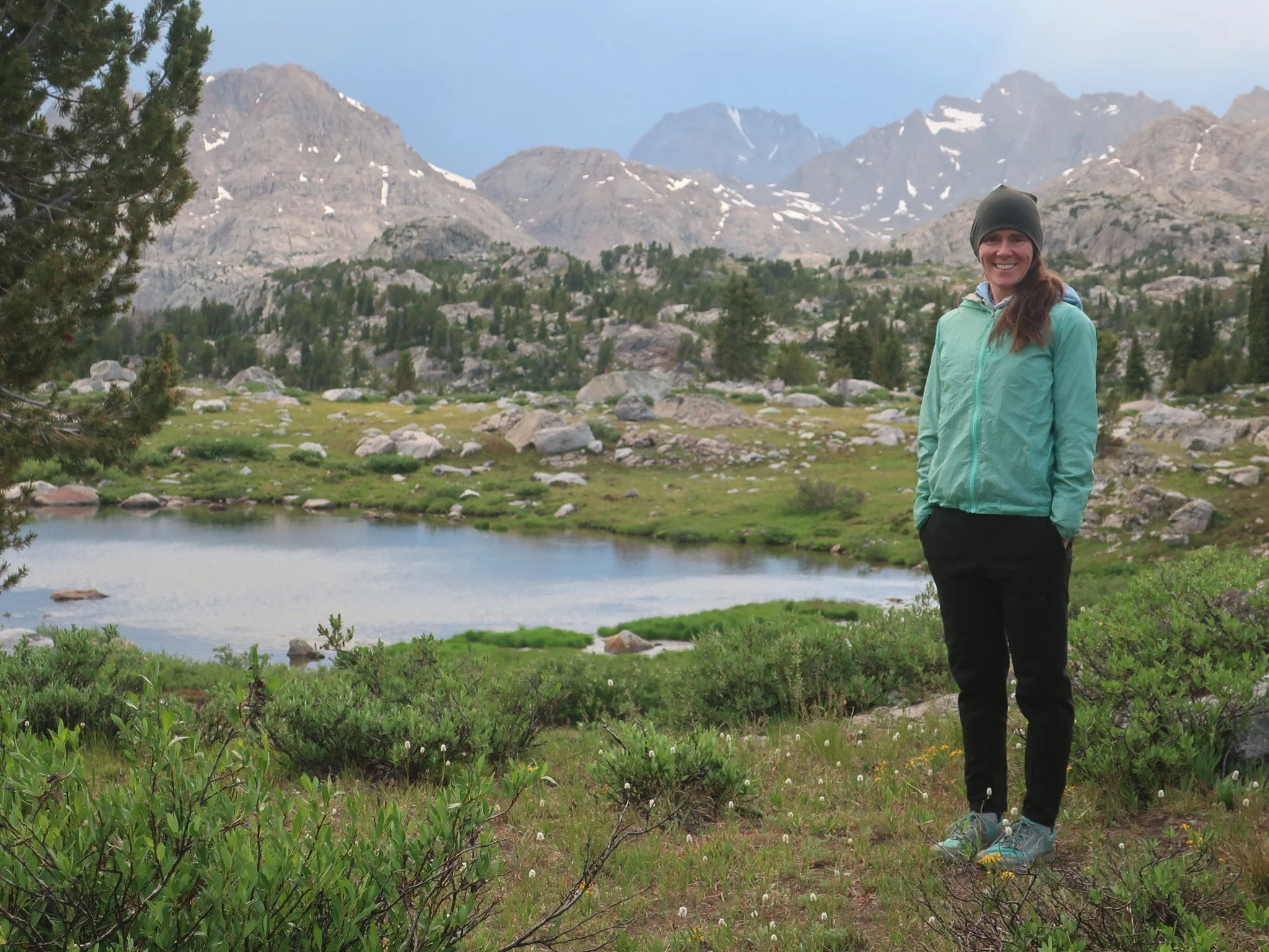 Laura Schmidt standing outdoors in a mountain landscape, representing her grounded and nature-based approach to IFS work