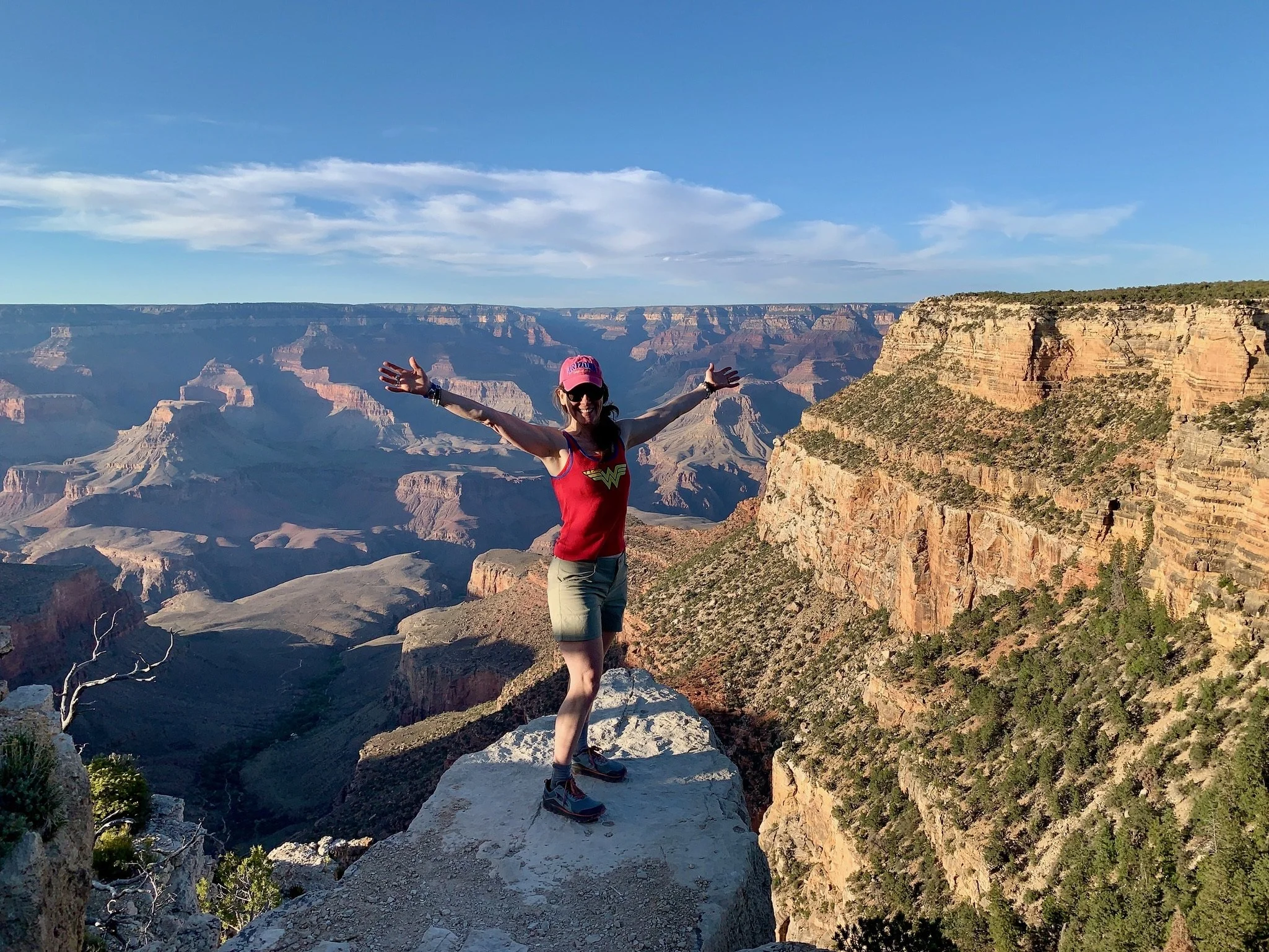 Person standing at the edge of the Grand Canyon with arms open, expressing freedom and expansion