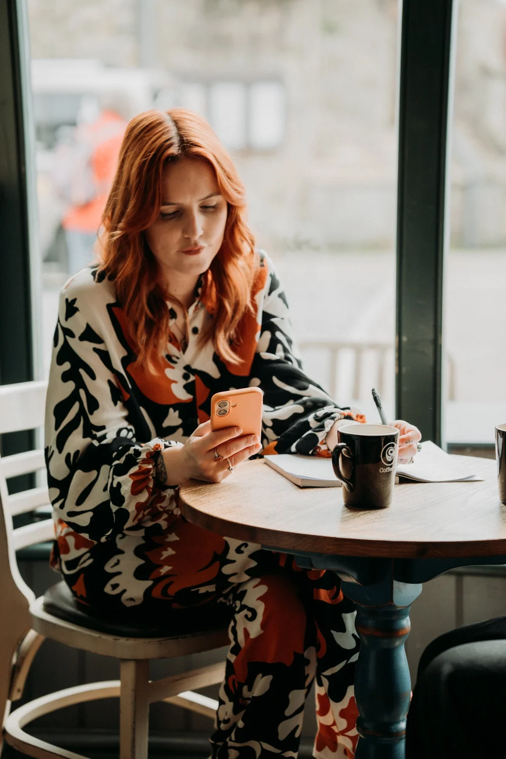 Emma Thompson, The Sales Therapist, sitting at a café table with a notebook