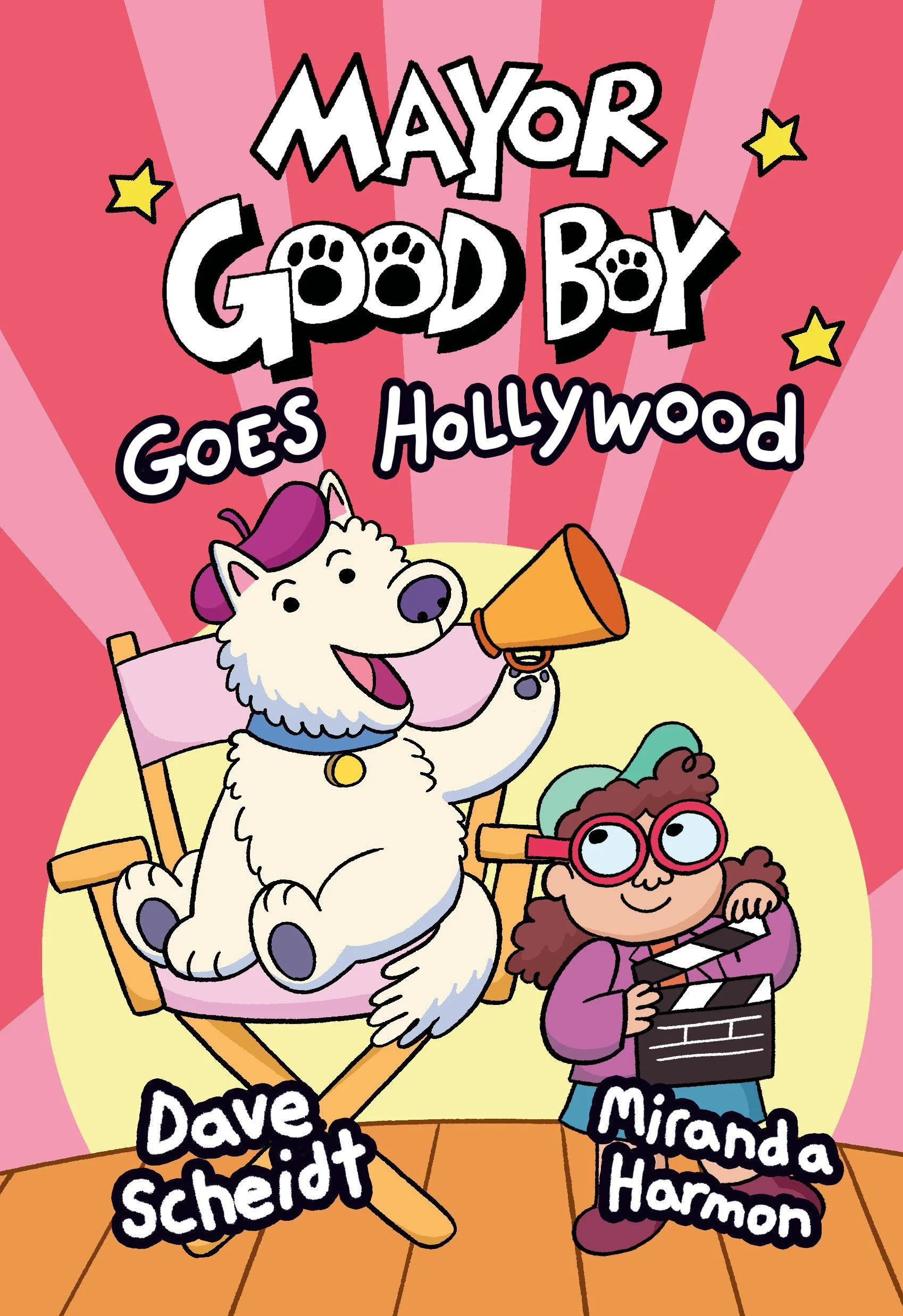 Cover of the book "Mayor Good Boy Goes Hollywood" featuring a white dog with purple hair, sitting in a pink director's chair, holding a megaphone, and smiling. A girl with curly brown hair, glasses, and a green hat stands next to him, holding a direc