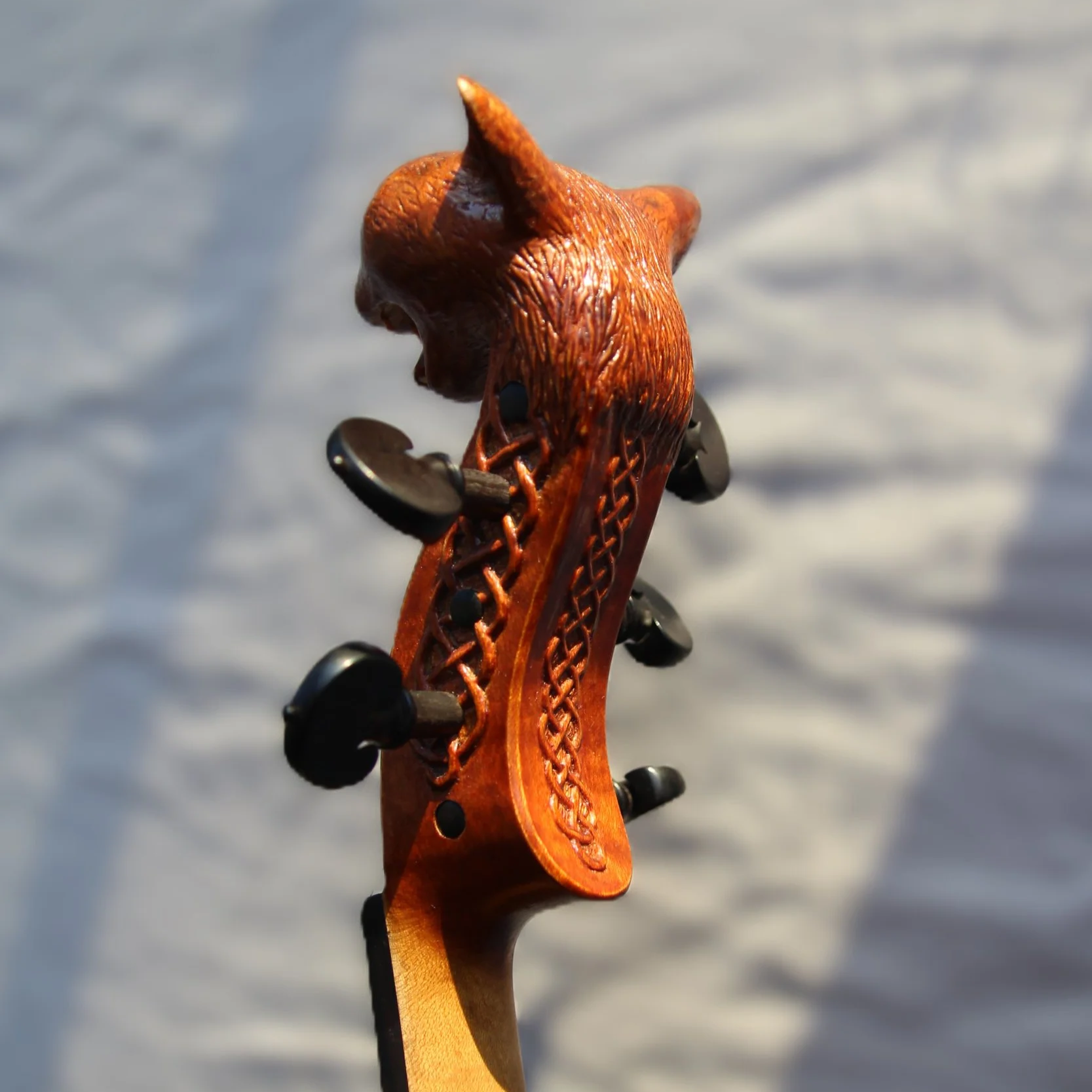 side view of 5-string viola scroll with cat head carving and decoration