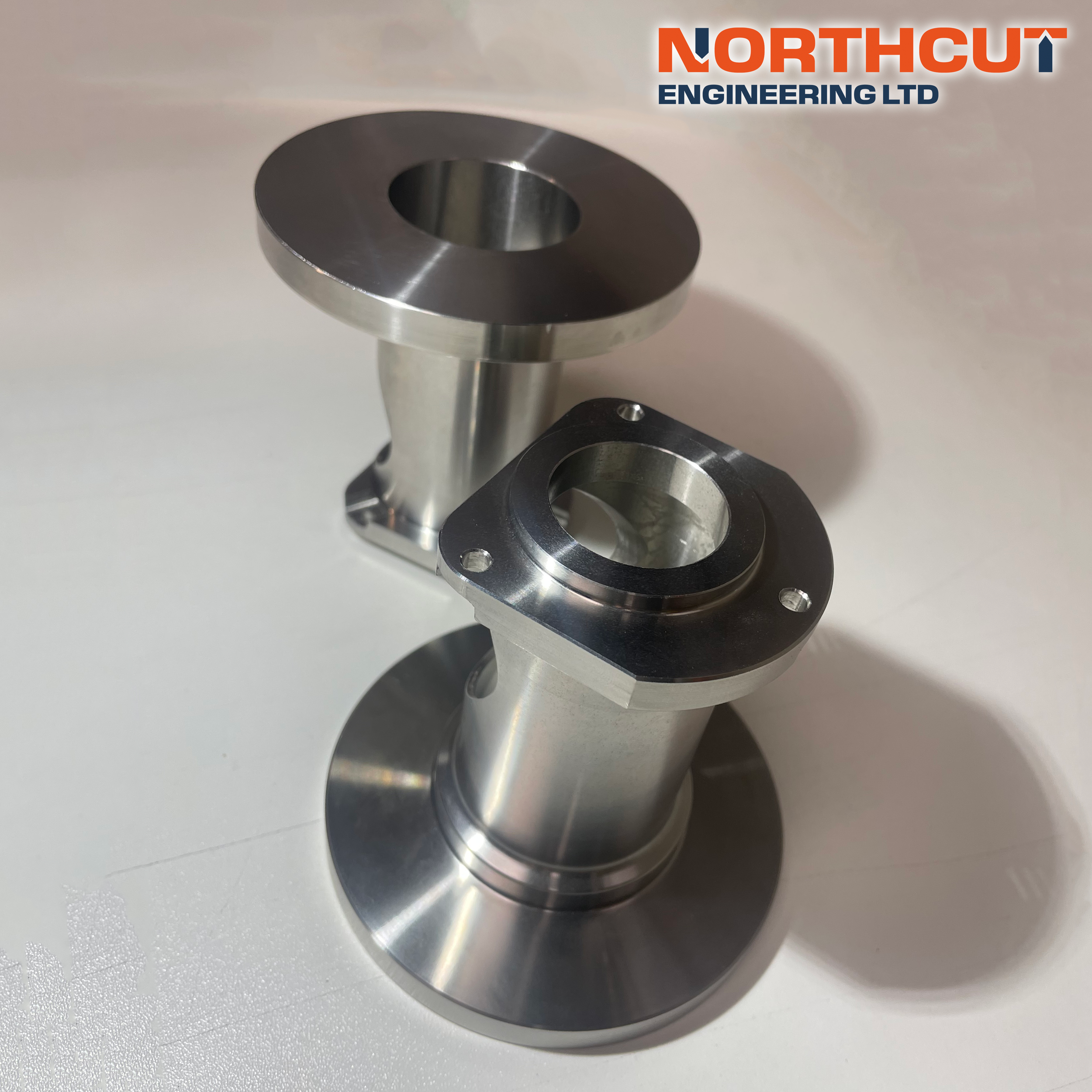 Three metal machined rings with flange holes placed on a white surface, with a logo of Northcut Engineering Ltd in the top right corner.