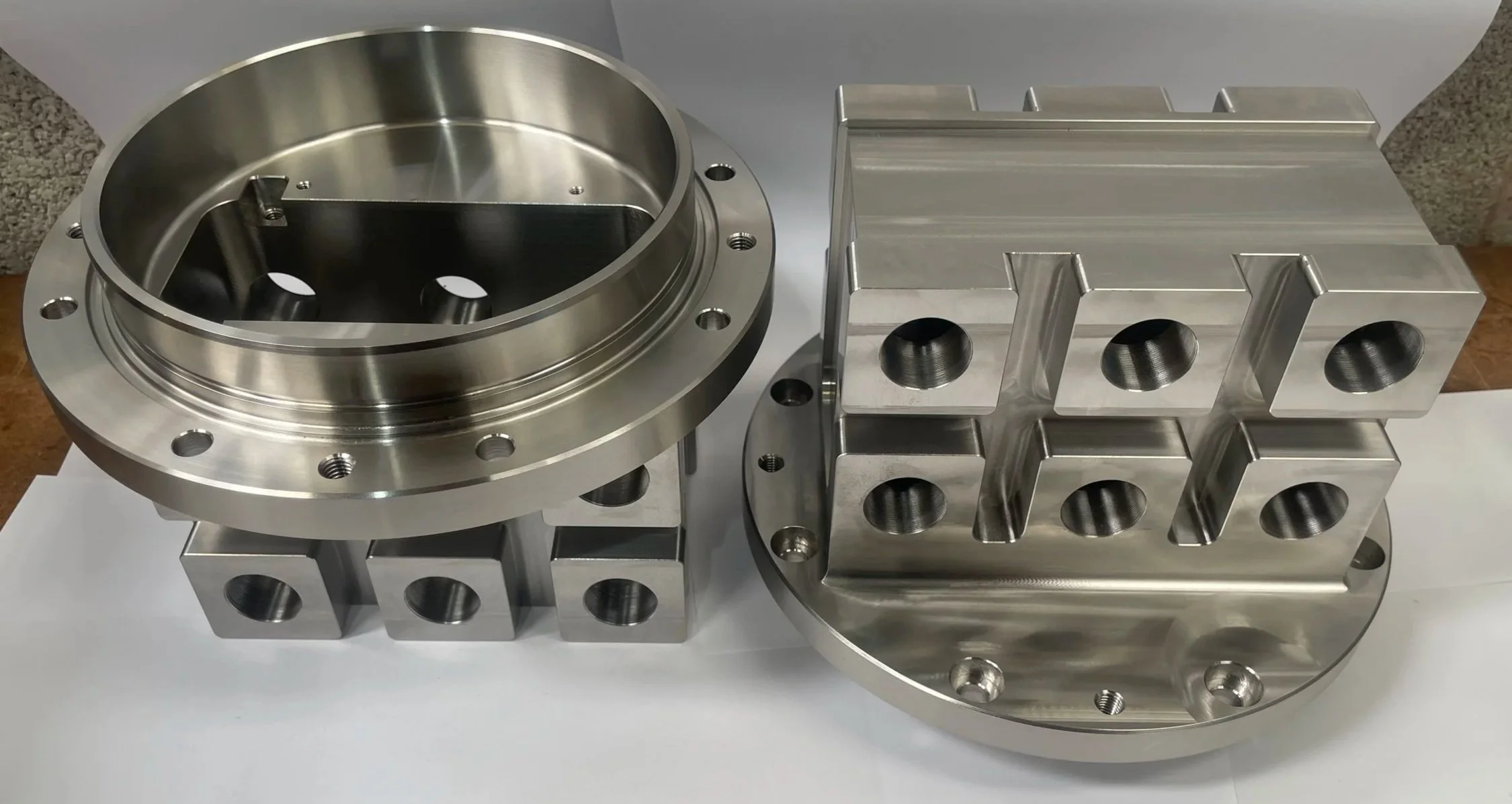 Two large, machined metal parts with circular and rectangular holes, possibly components of industrial equipment or machinery.