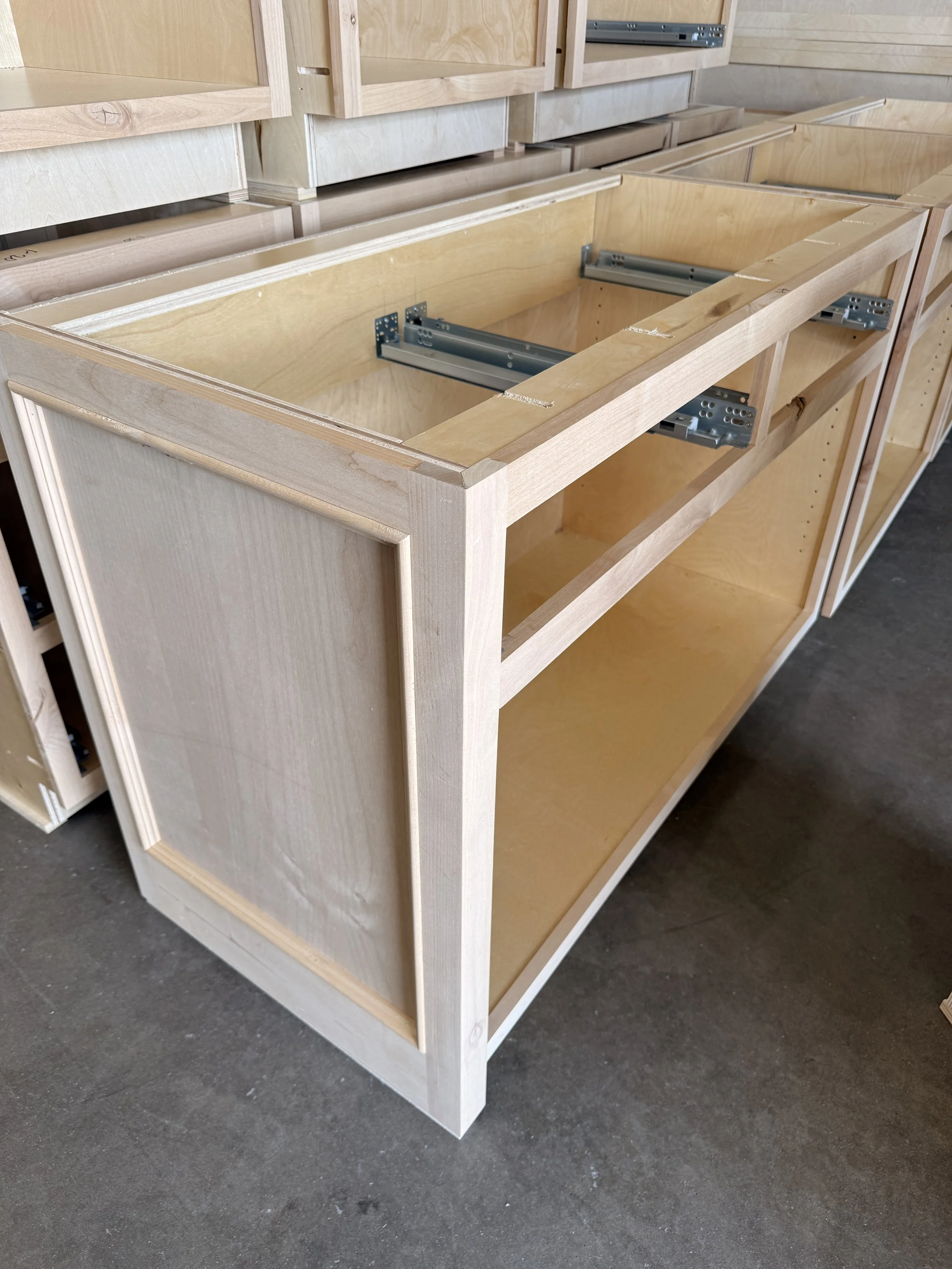 Unfinished wooden cabinets being assembled in a workshop or construction site.