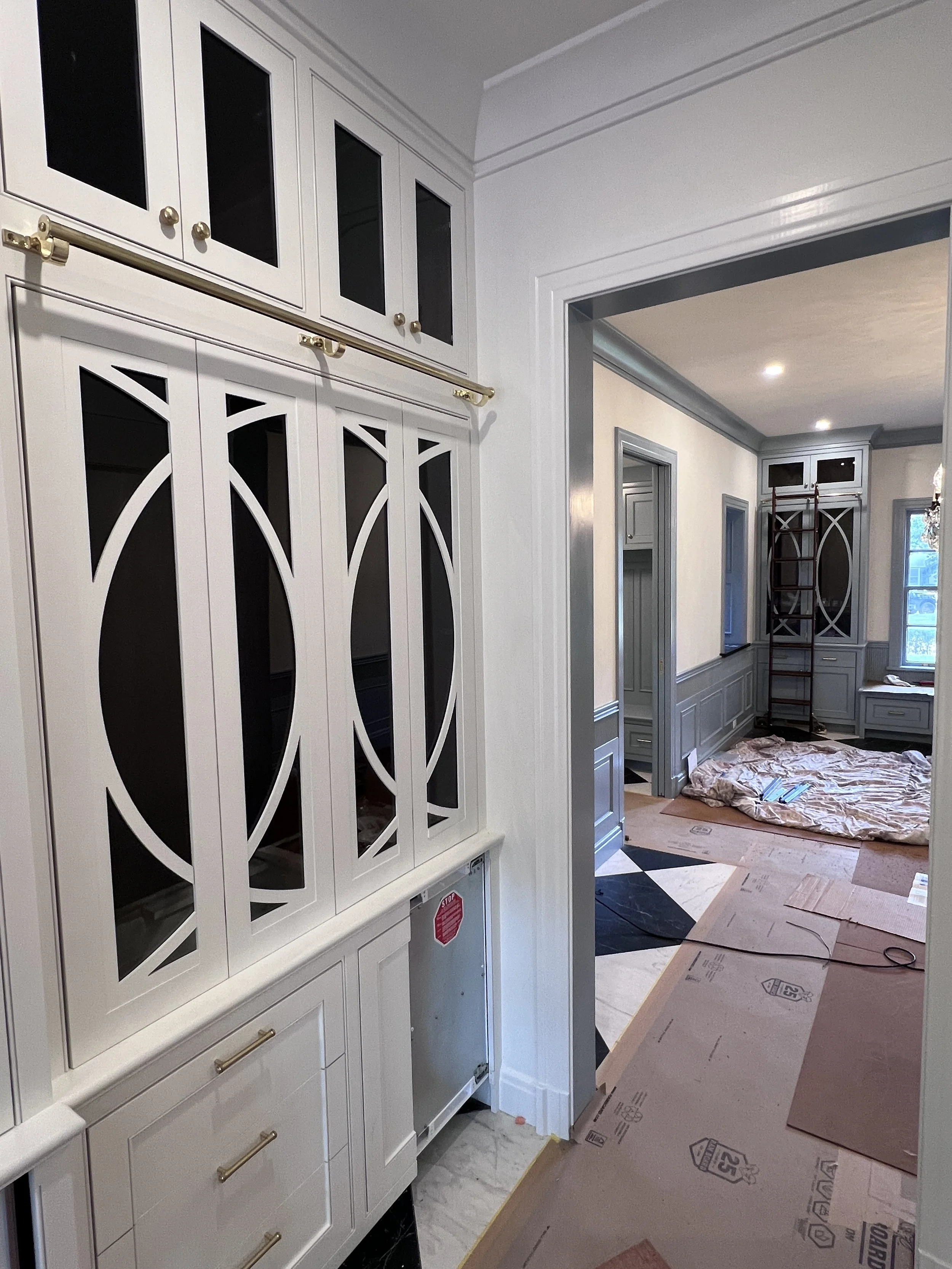 An interior room under renovation with white and gray cabinetry, partially installed, and various construction materials on the floor.