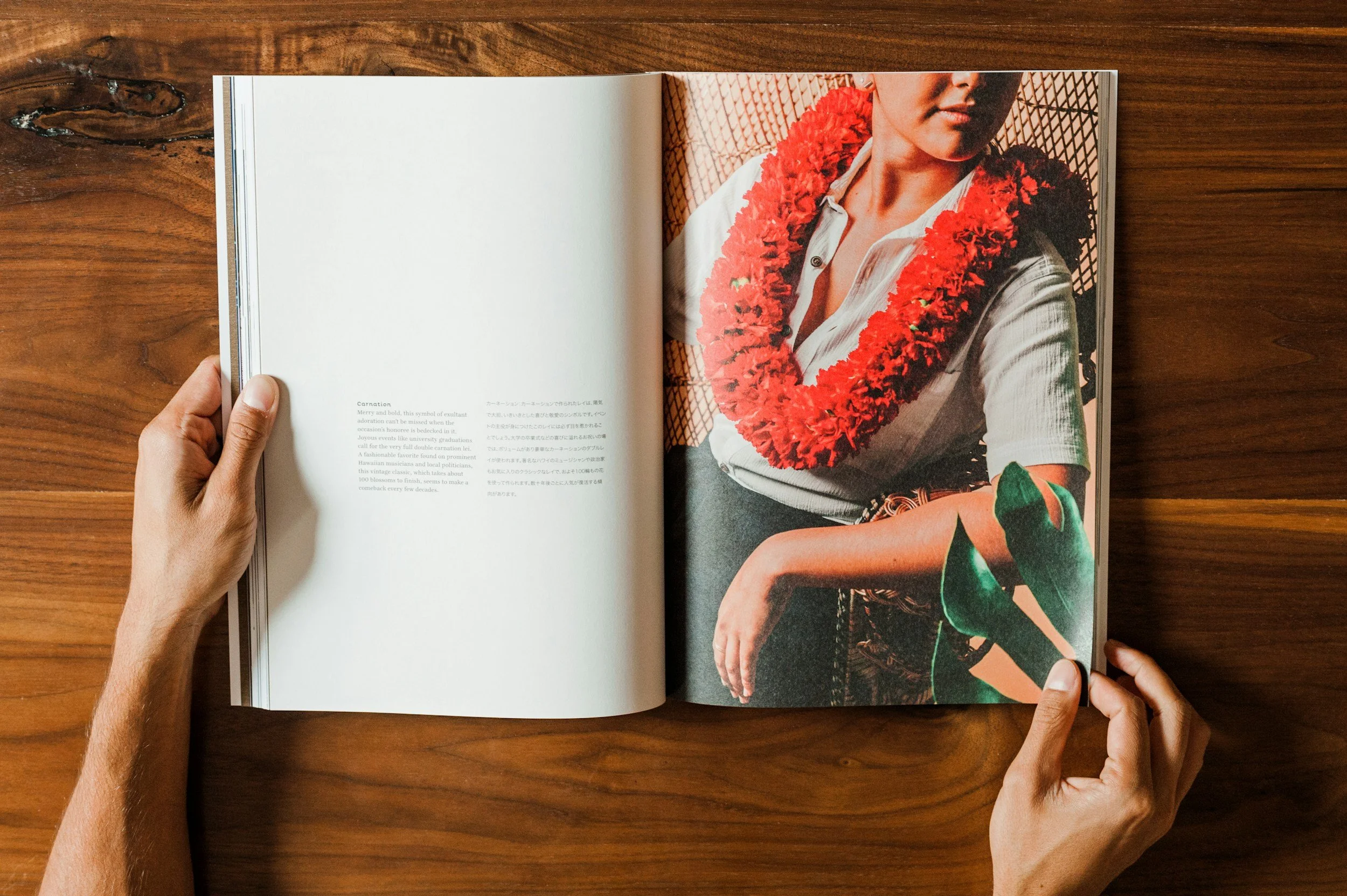 Open magazine on a wooden surface, showing a woman wearing a floral lei and casual clothing.