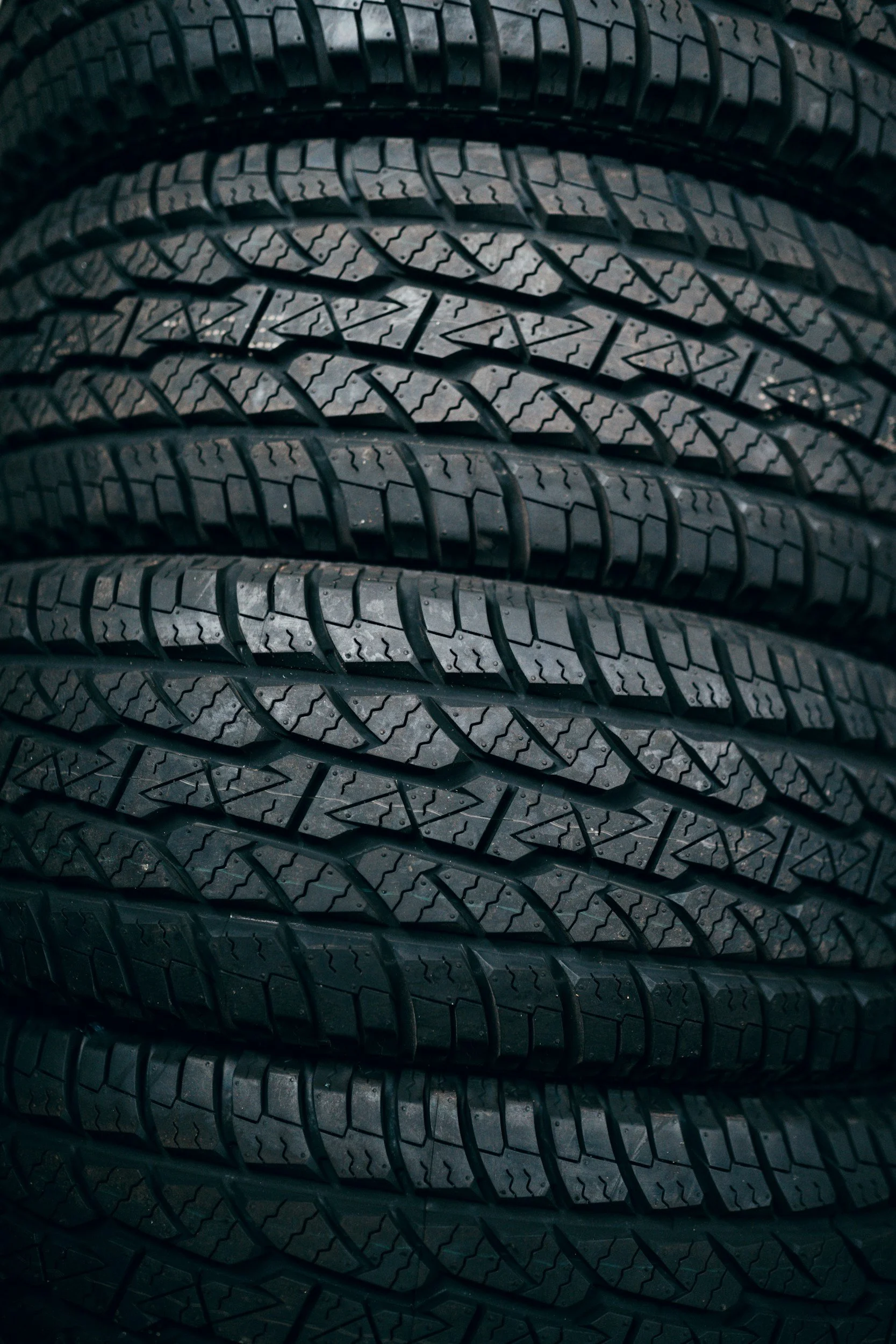 Close-up of stacked black car tires showing detailed tread pattern.