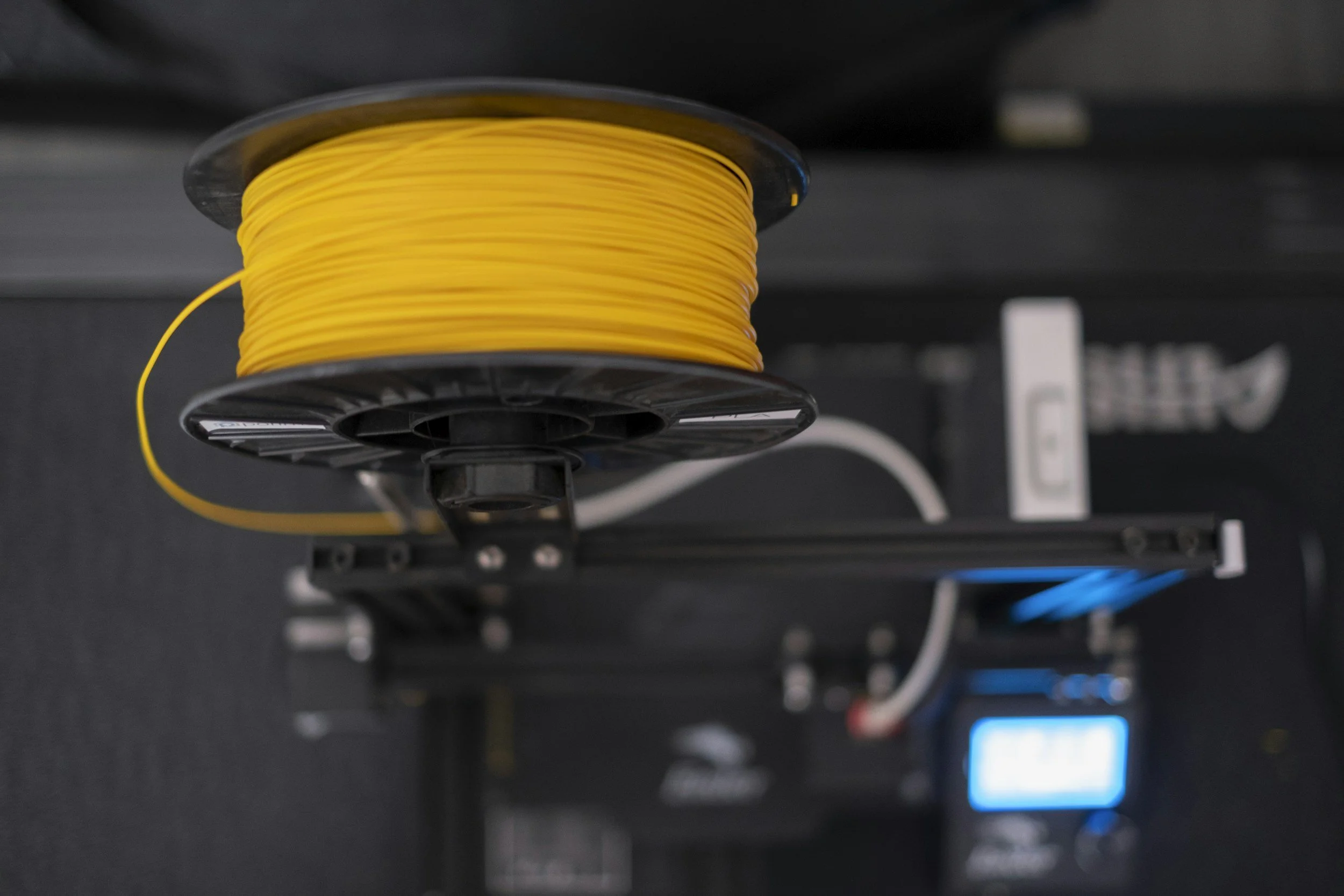 A spool of yellow filament on a 3D printer