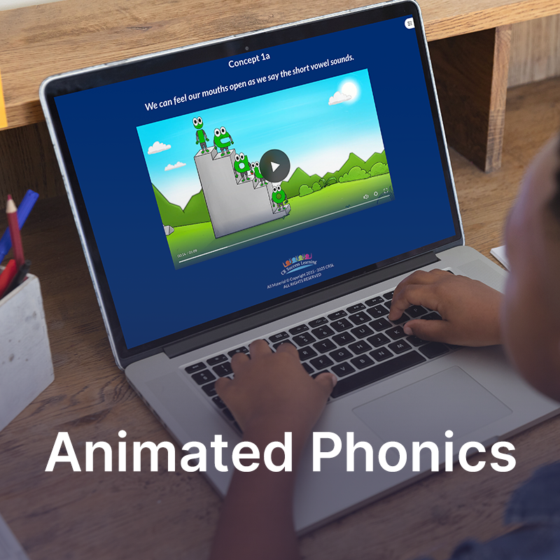 A young reader sitting at a desk using a laptop to view an animated educational video about phonics, with the title 'Animated Phonics' on the screen.