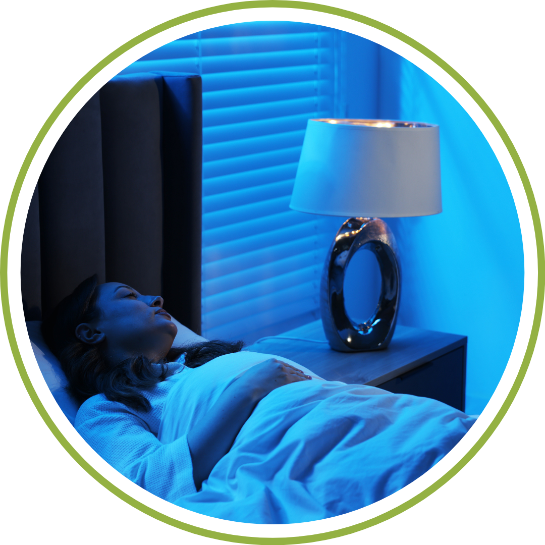 A cozy, dimly lit bedroom where a postpartum doula gently hands a sleeping newborn baby back to her resting mom in bed.