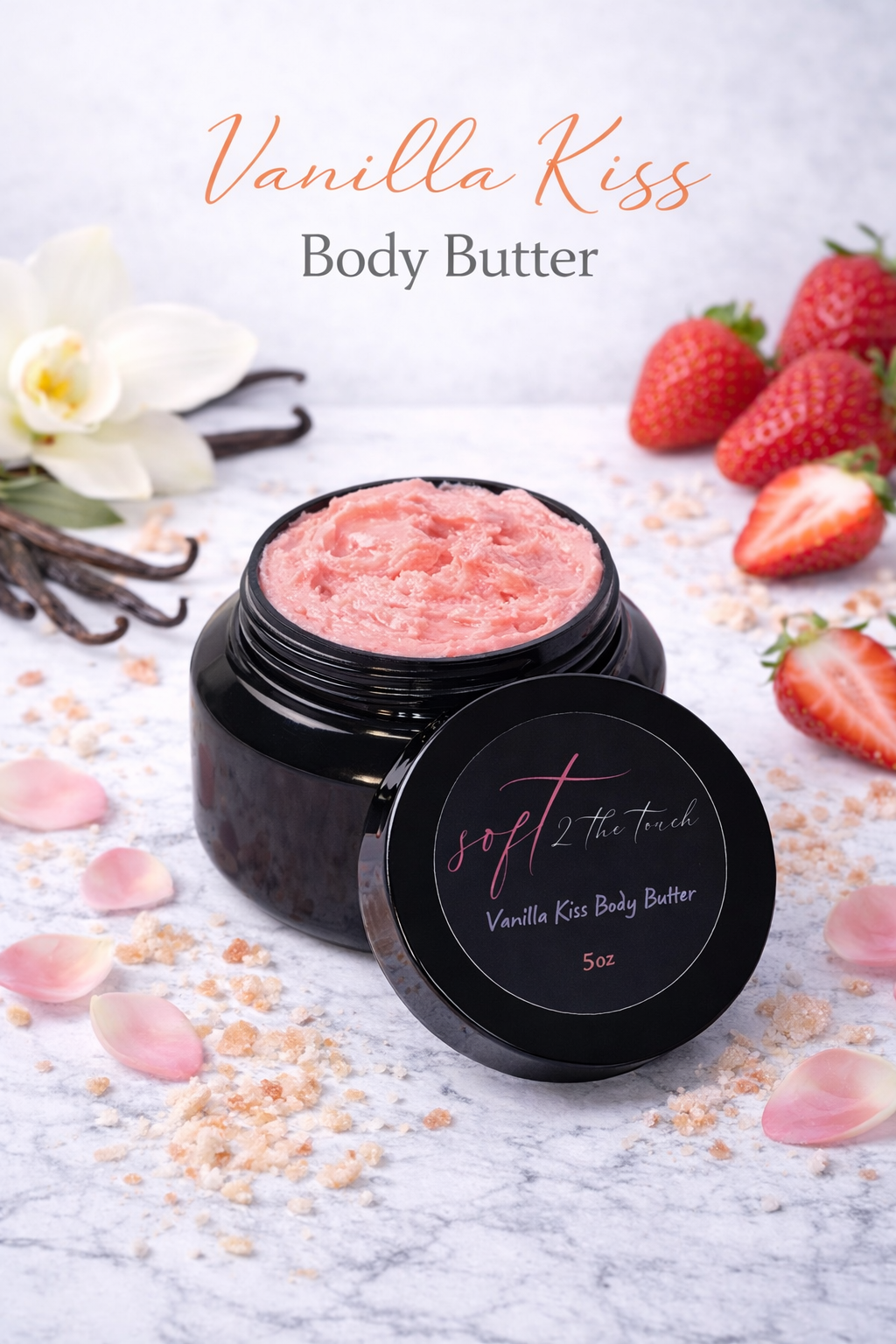 A black jar of Vanilla Kiss Body Butter with pink content, surrounded by strawberries, flower petals, and vanilla beans on a white surface with a soft background.