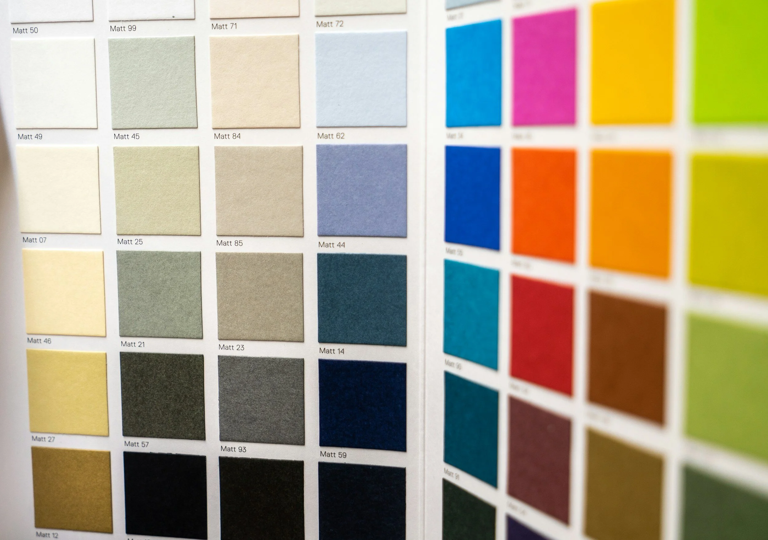 Color swatch sample book displaying a wide range of matte color options, including neutral, blue, green, and vibrant warm tones