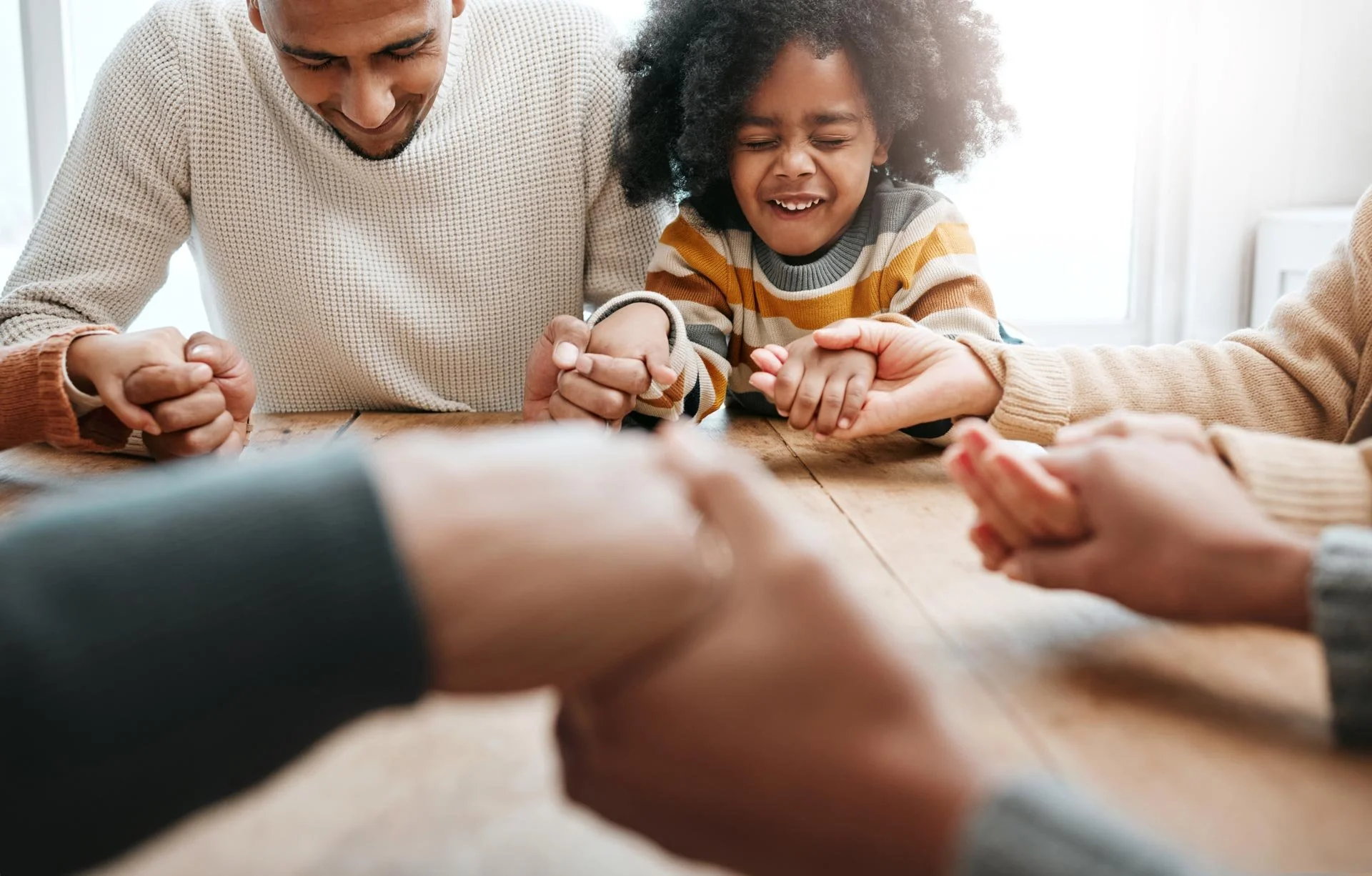 Family holding hands in prayer during a church service, expressing faith, worship, gratitude, and spiritual connection across generations