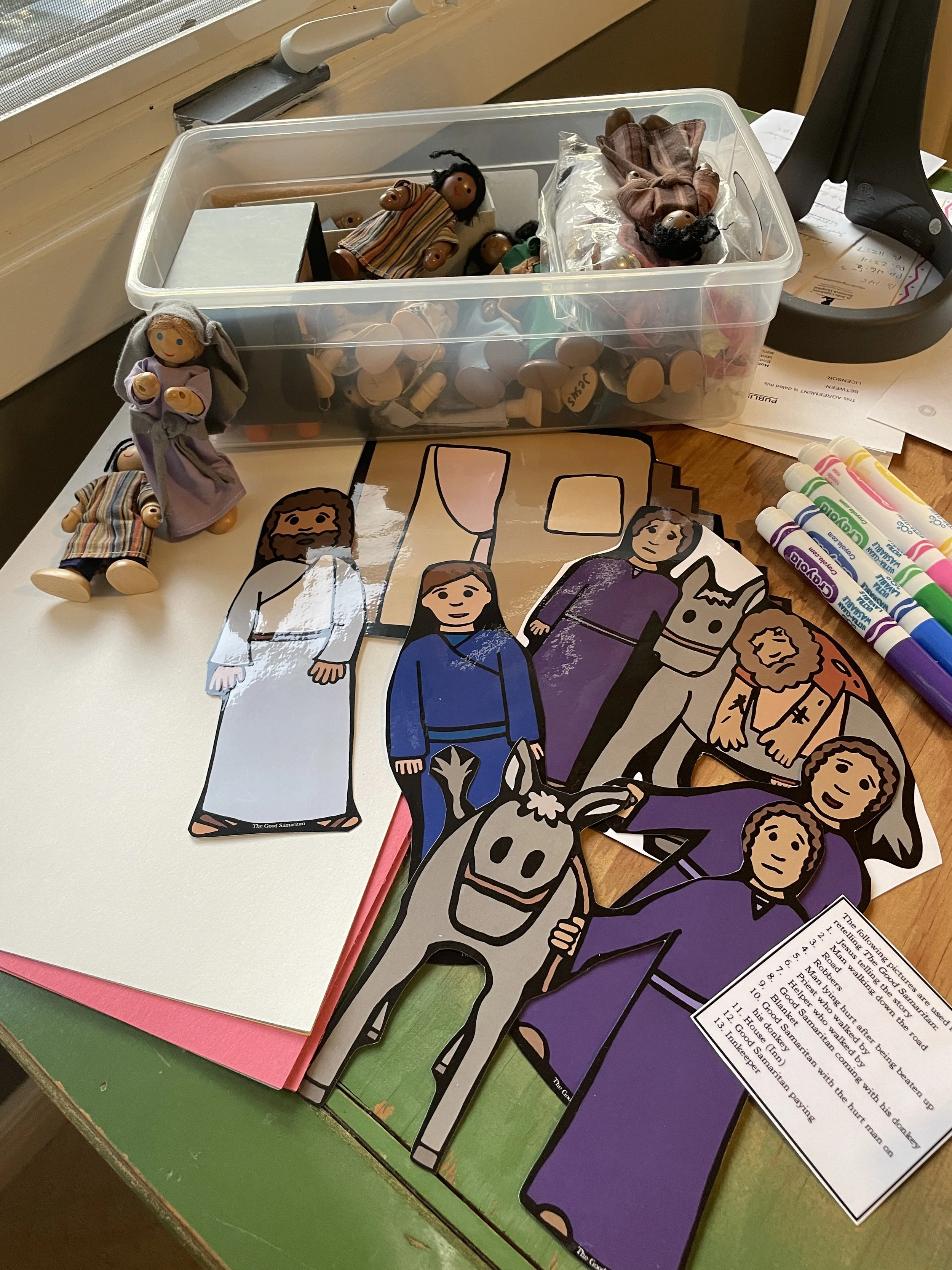 Children’s Bible curriculum materials including paper cutouts of biblical characters and a donkey, small dolls, and classroom supplies for interactive Sunday school activities.