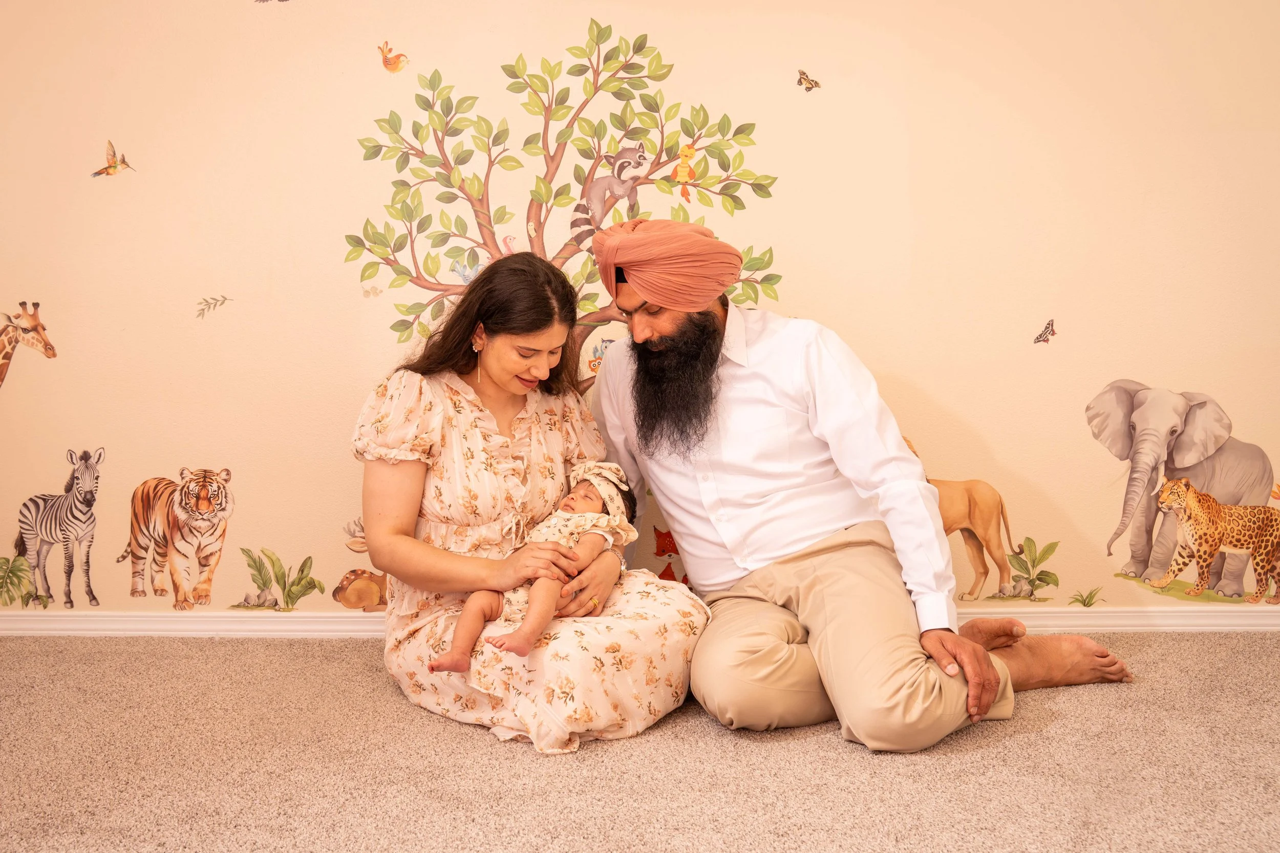 Happy mon, dad and baby relaxing together in a cozy nursery during an at-home family photo session in Puyallup, Washington.