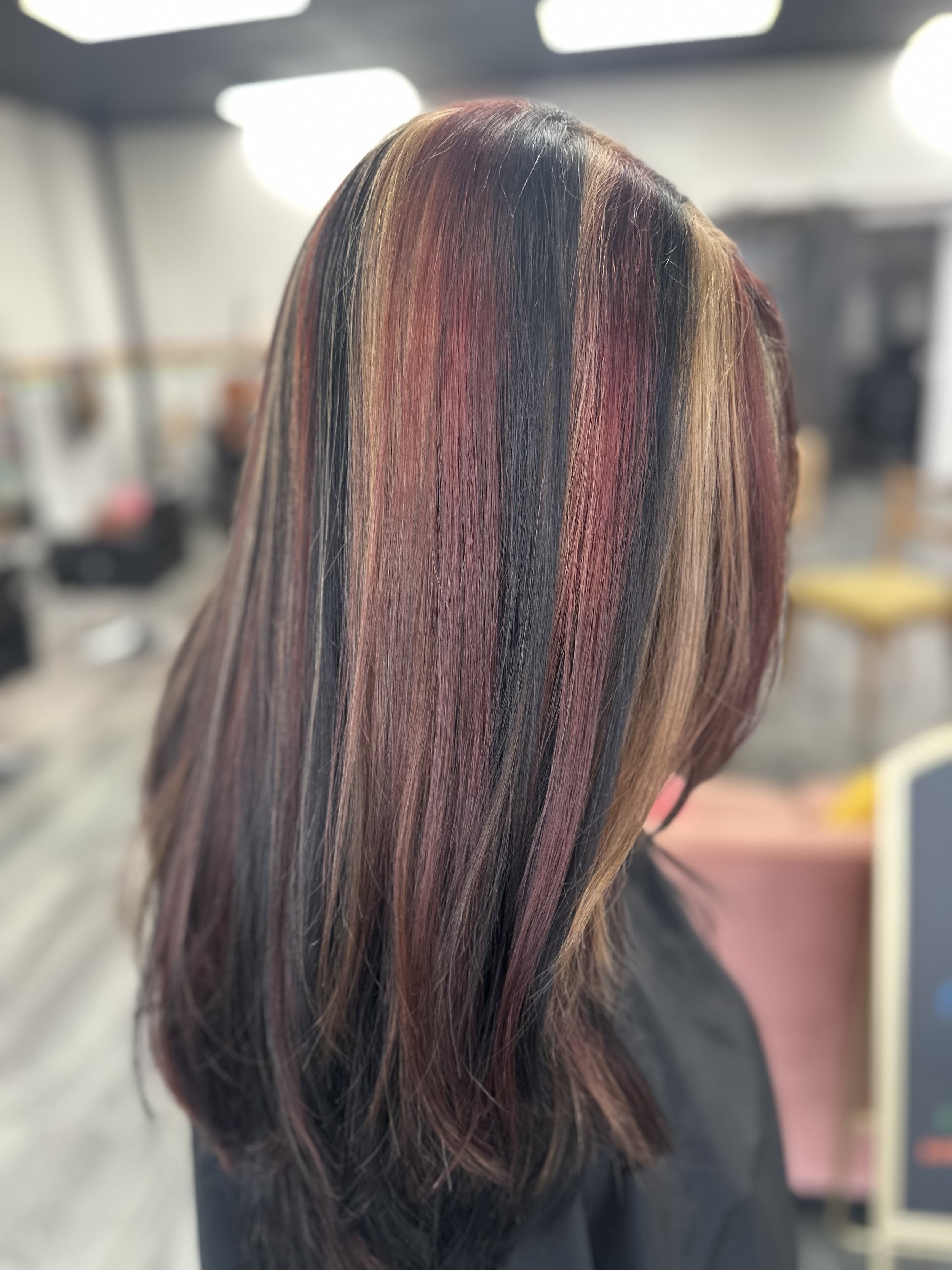 Long hair with multiple colors including black, red, and shades of blonde, styled straight.