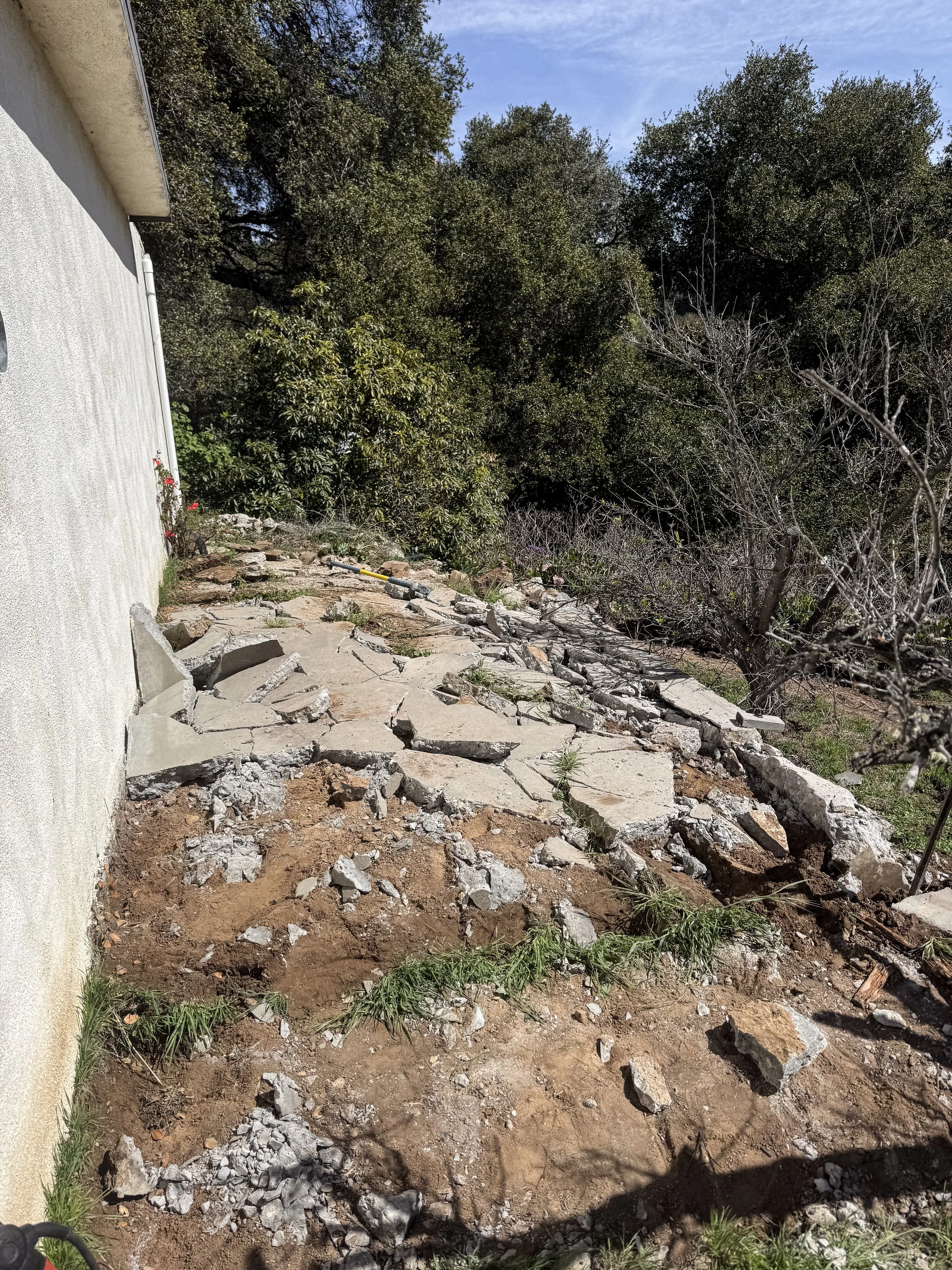 Broken concrete debris in the backyard of a home.