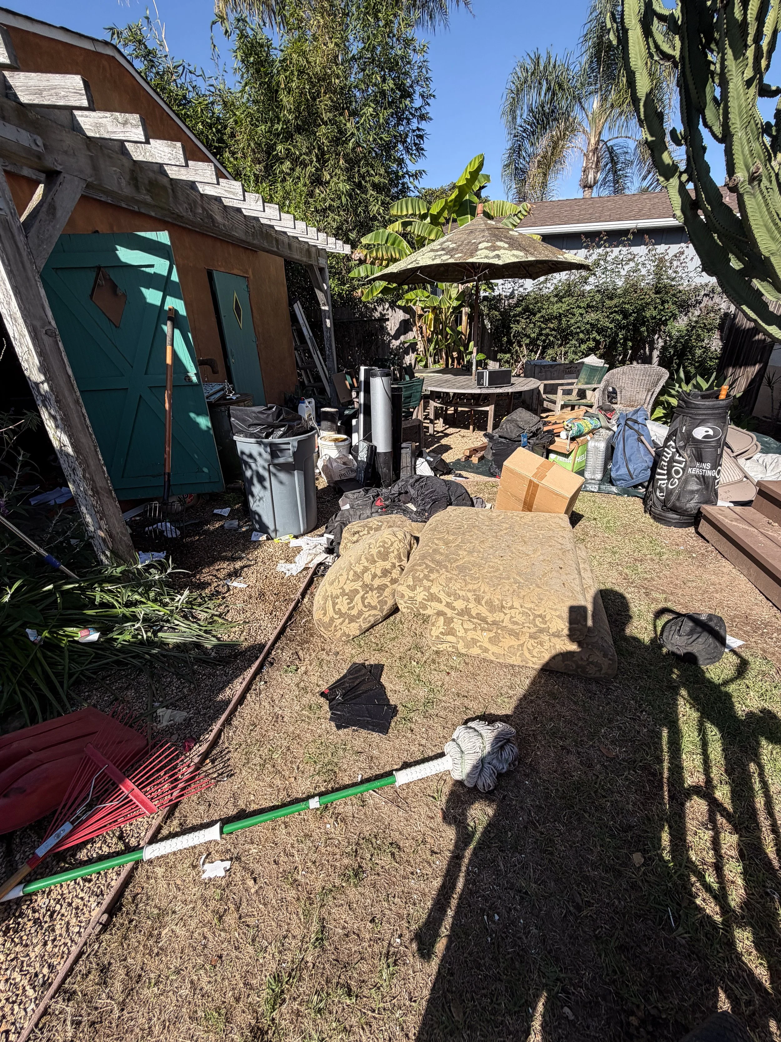 A backyard filled with old sofa cushions and other junk.