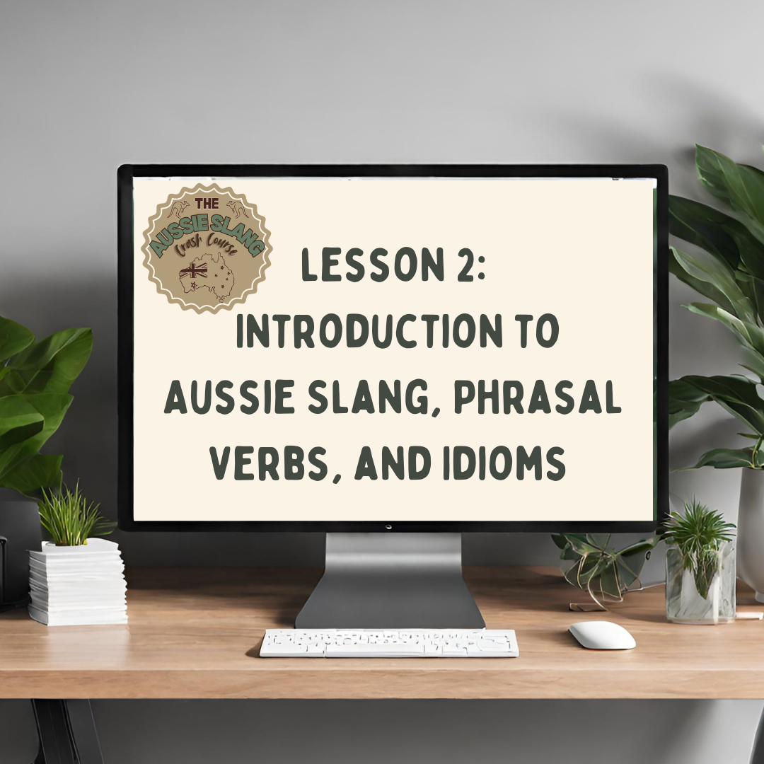Computer monitor displaying "Lesson 2: Introduction to Aussie Slang, Phrasal Verbs, and Idioms" with decorative plants and a keyboard on a desk.