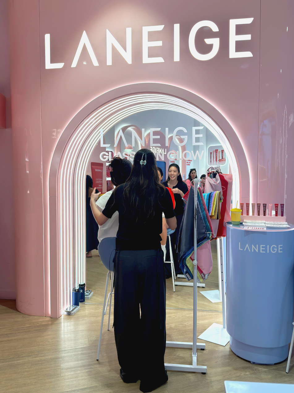 Beauty color analysis event- People inside a LANEIGE store with pink walls and neon signs, browsing skincare products and makeup products through color analysis.