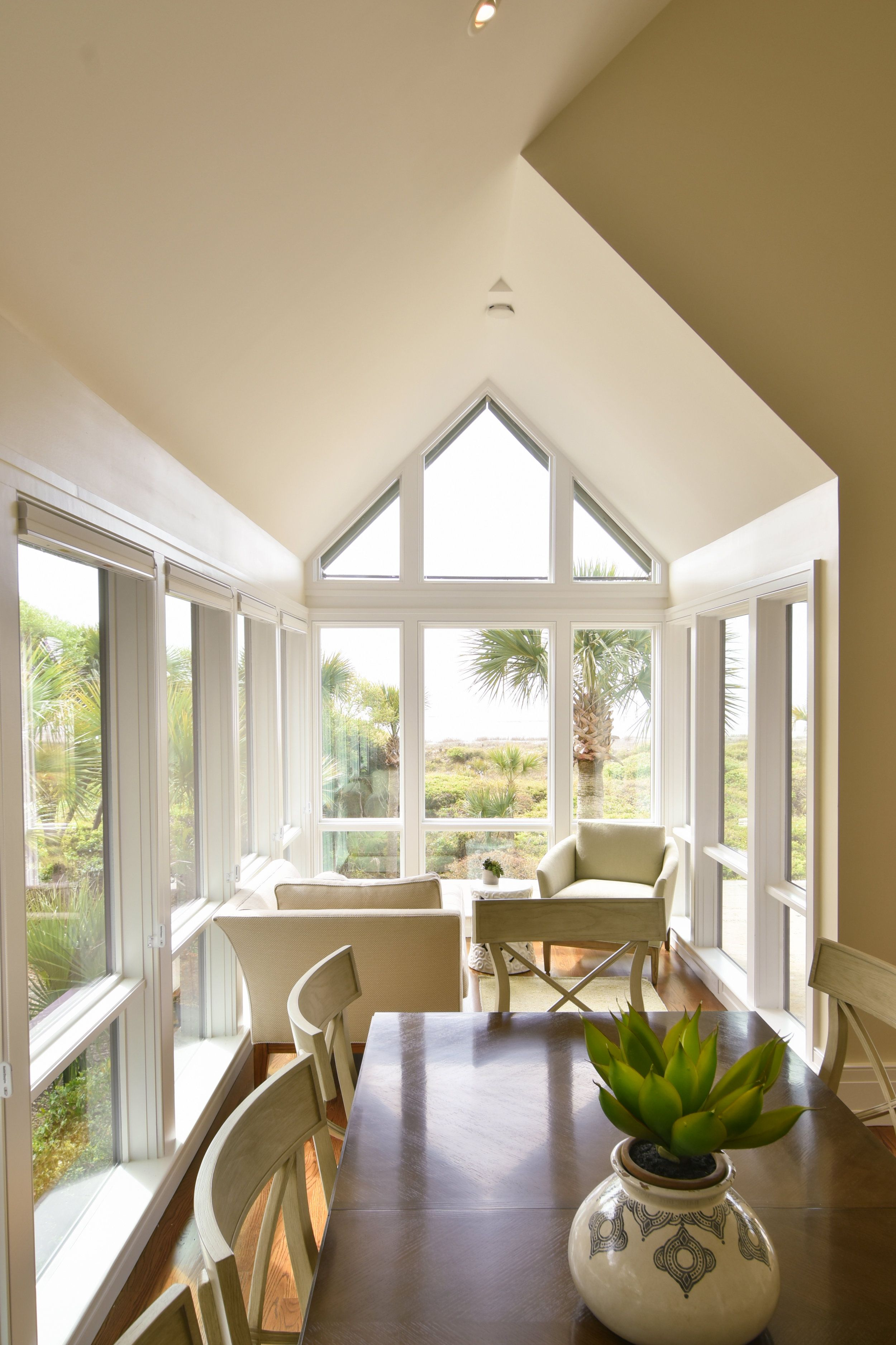 A neutral-toned coastal nook featuring a comfy chaise lounge and chair in a glass-encased window area overlooking Kiawah Island, South Carolina.