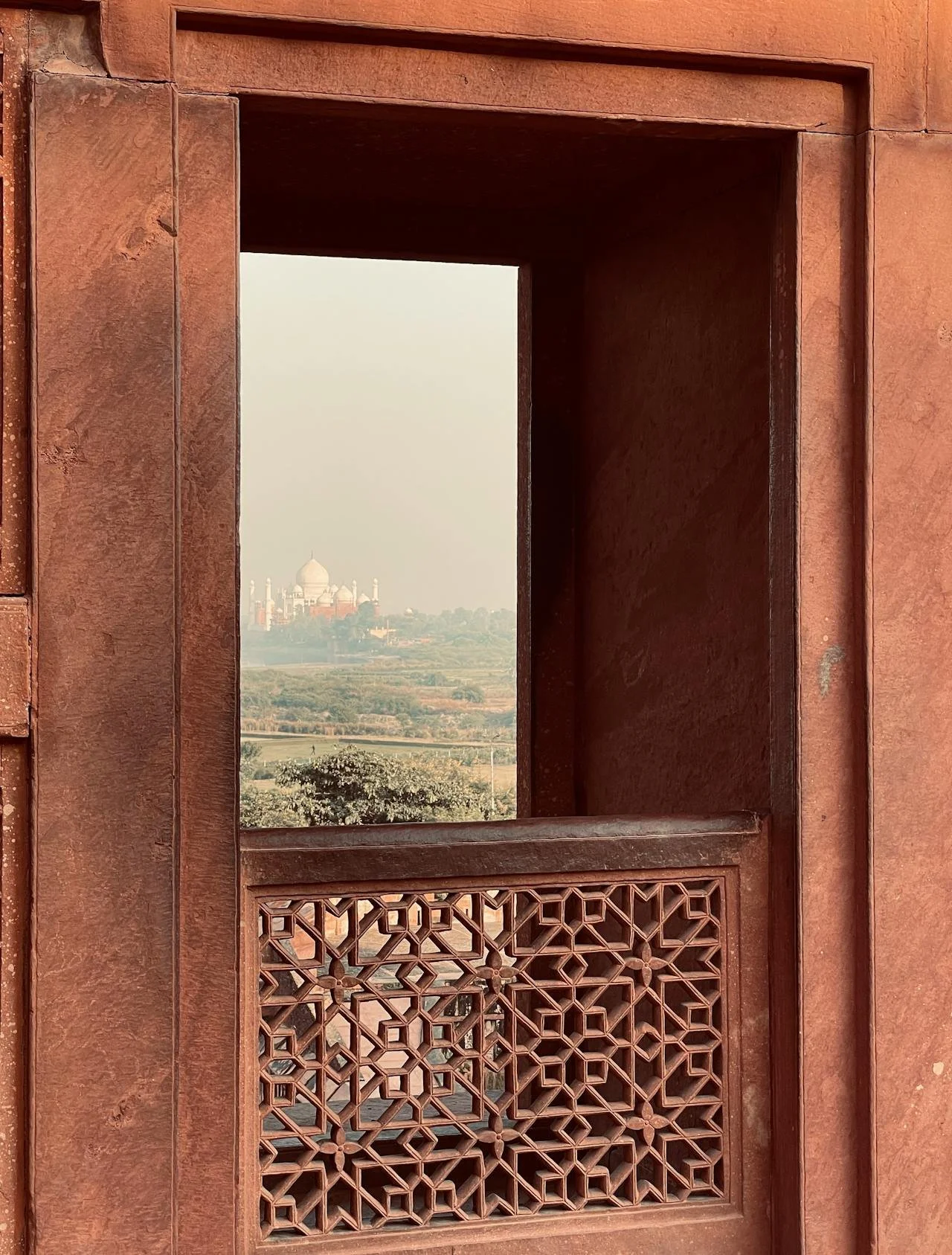 Traditional Indian Jali pierced screen design in the foreground with the Taj Mahal in the background.
