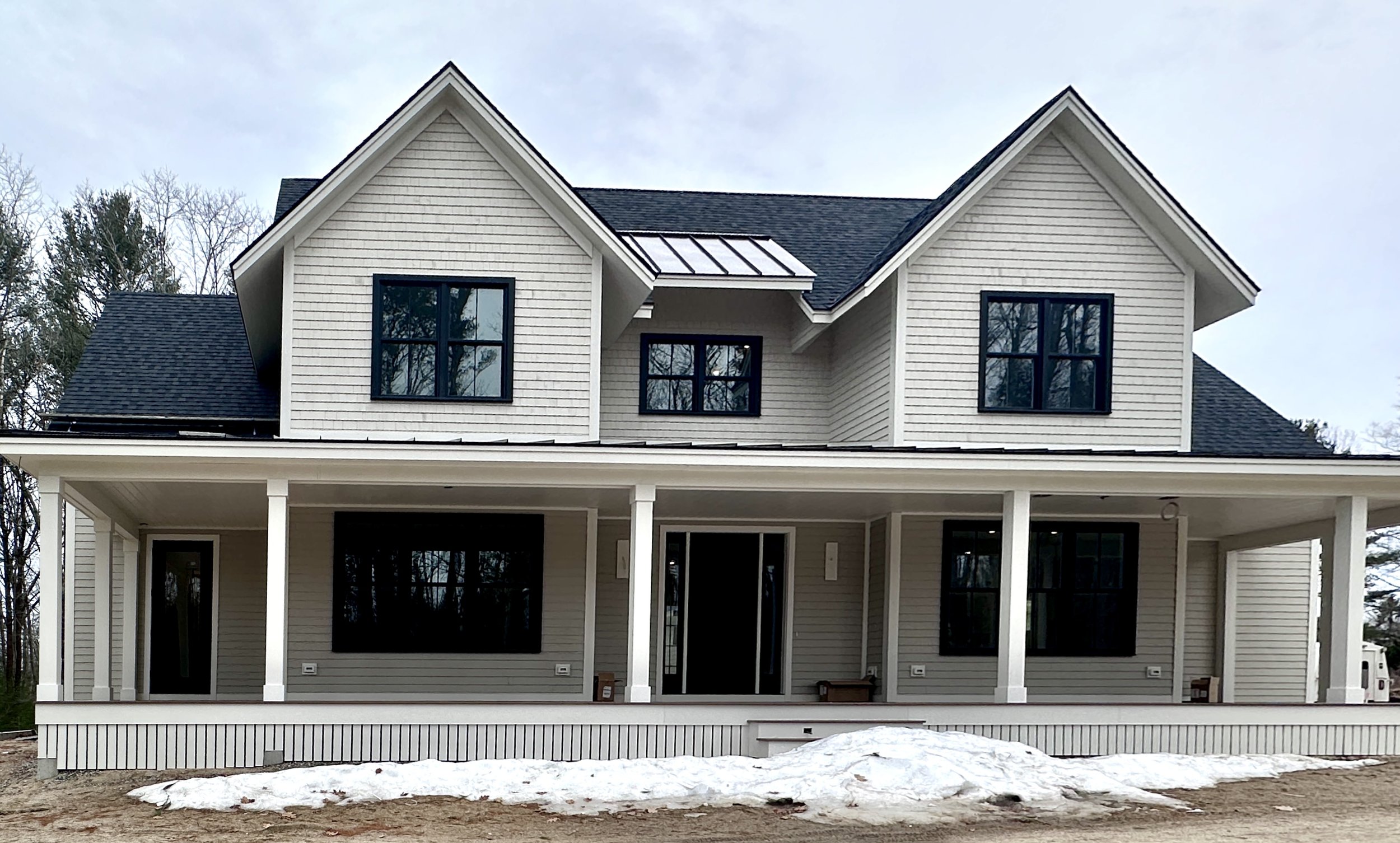 Progress shot of a new build project in Kennebunkport, Maine, showing the architectural framing and natural wooded surroundings.