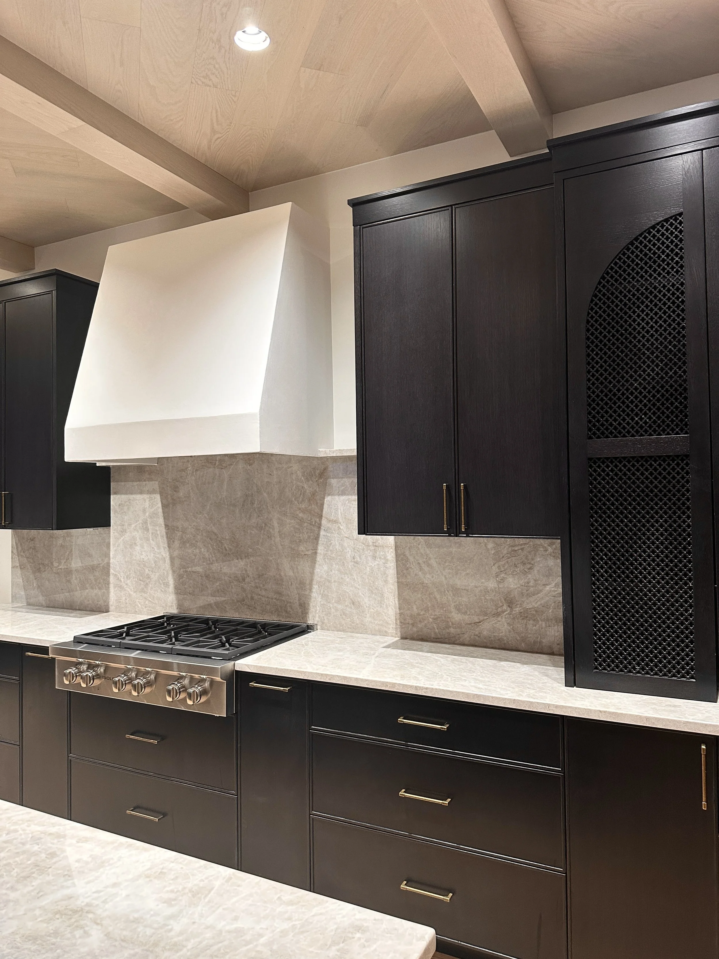 Hand-applied Italian plaster kitchen hood contrasting with dark wood cabinets and Taj Mahal quartzite.